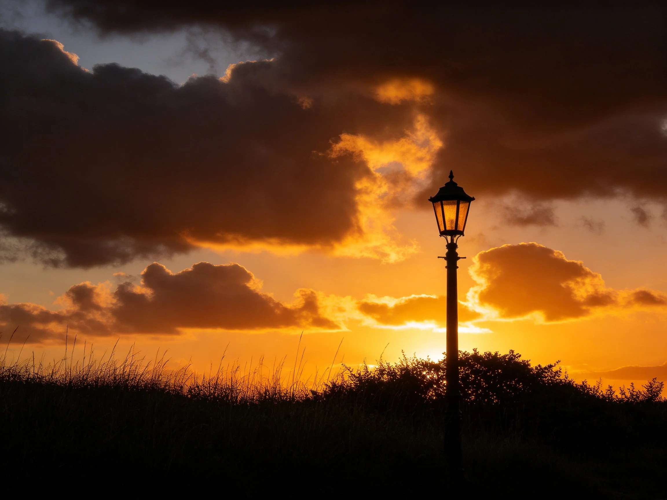 Dramatic sunset with golden clouds and vintage streetlamp
