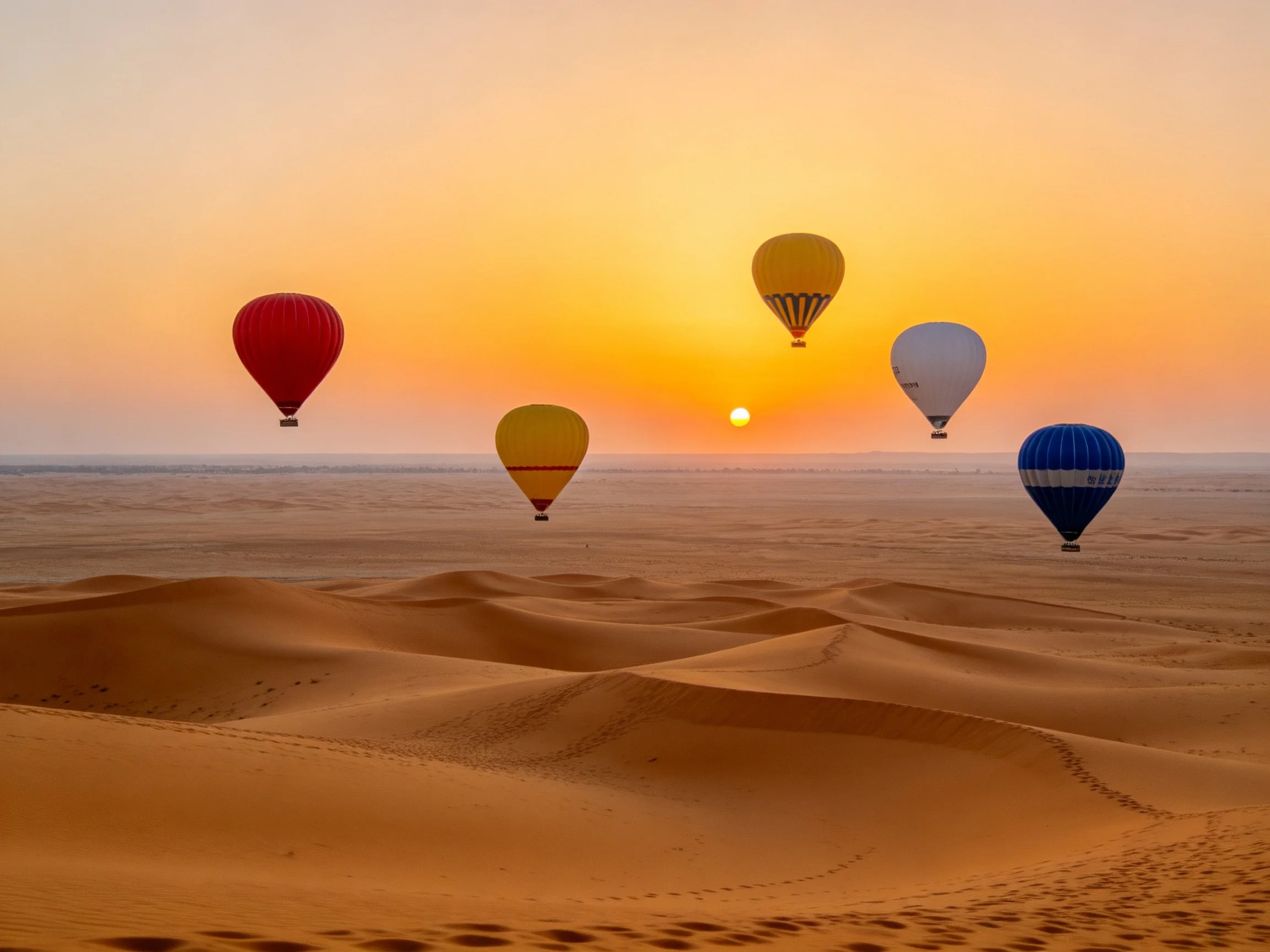 Five colorful hot air balloons floating over golden sand dunes at sunset