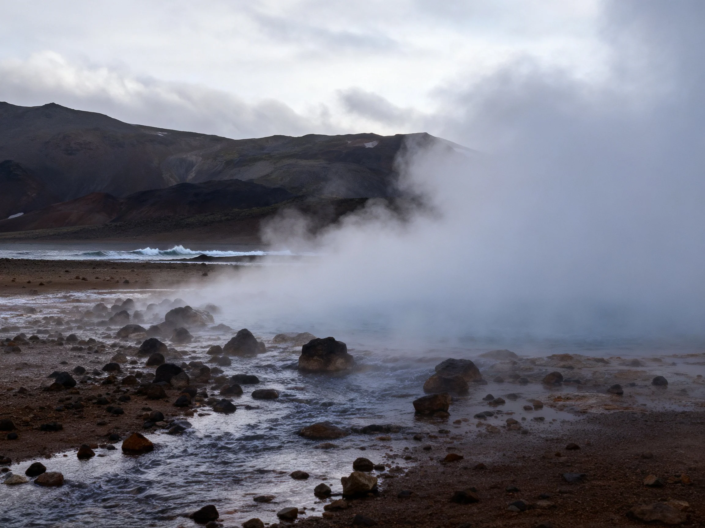 Geothermal Steam Field with Rocky Terrain and Mountainous Backdrop