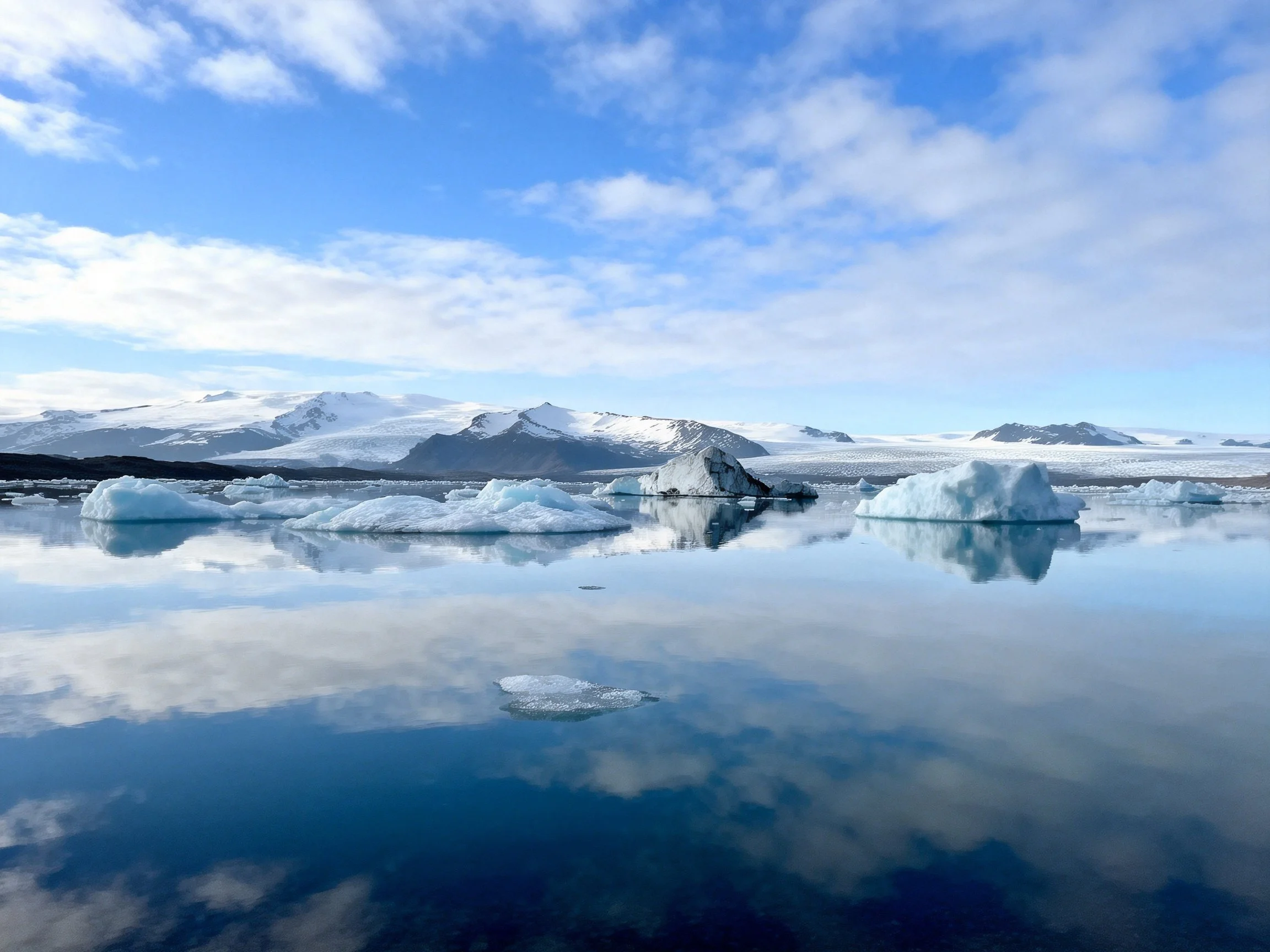 Glacial lagoon with floating icebergs and snowy mountains