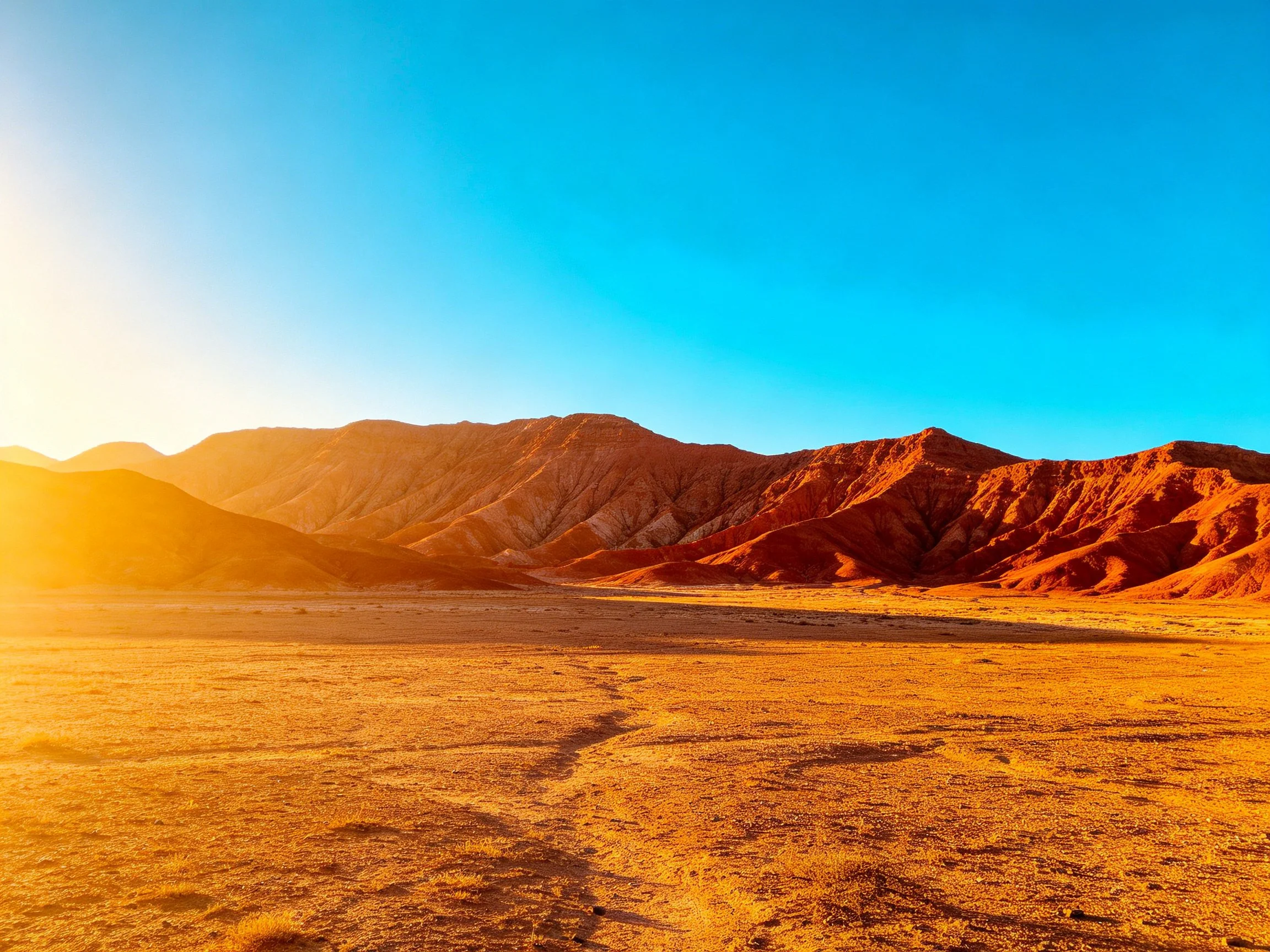 Golden Desert With Red Mountain Range Under Clear Blue Sky