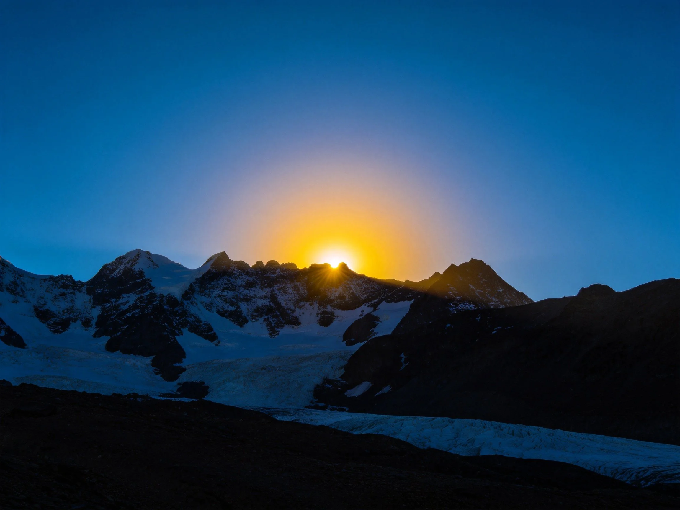 Golden Sunrise Behind Snow-Capped Mountain Peaks