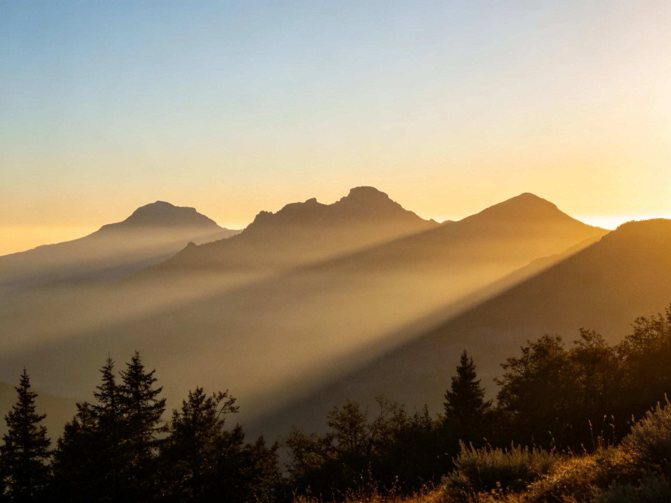 Golden Sunrise Rays Penetrate Misty Mountain Peaks