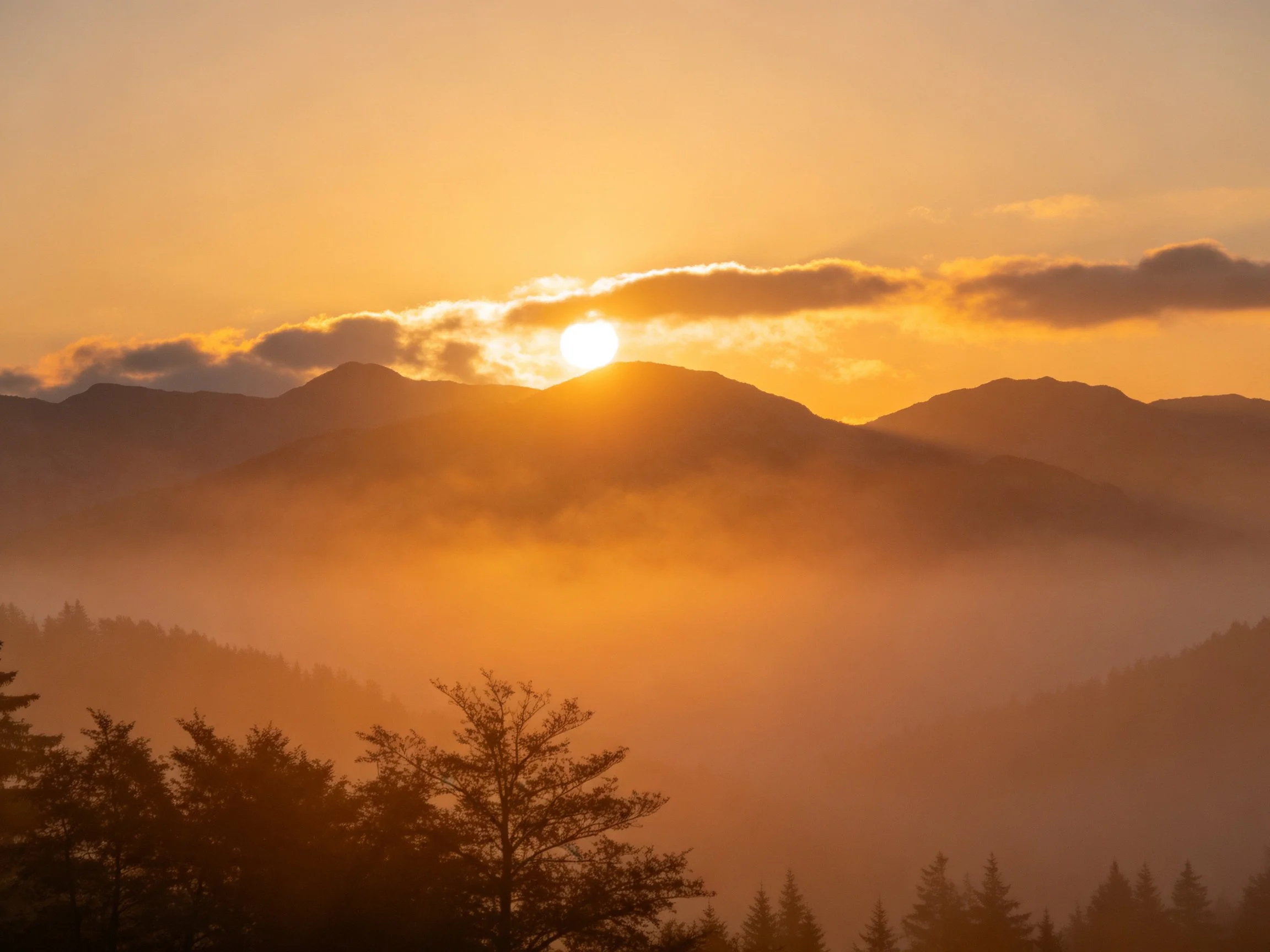 Golden Sunrise Through Clouds Over Misty Mountains