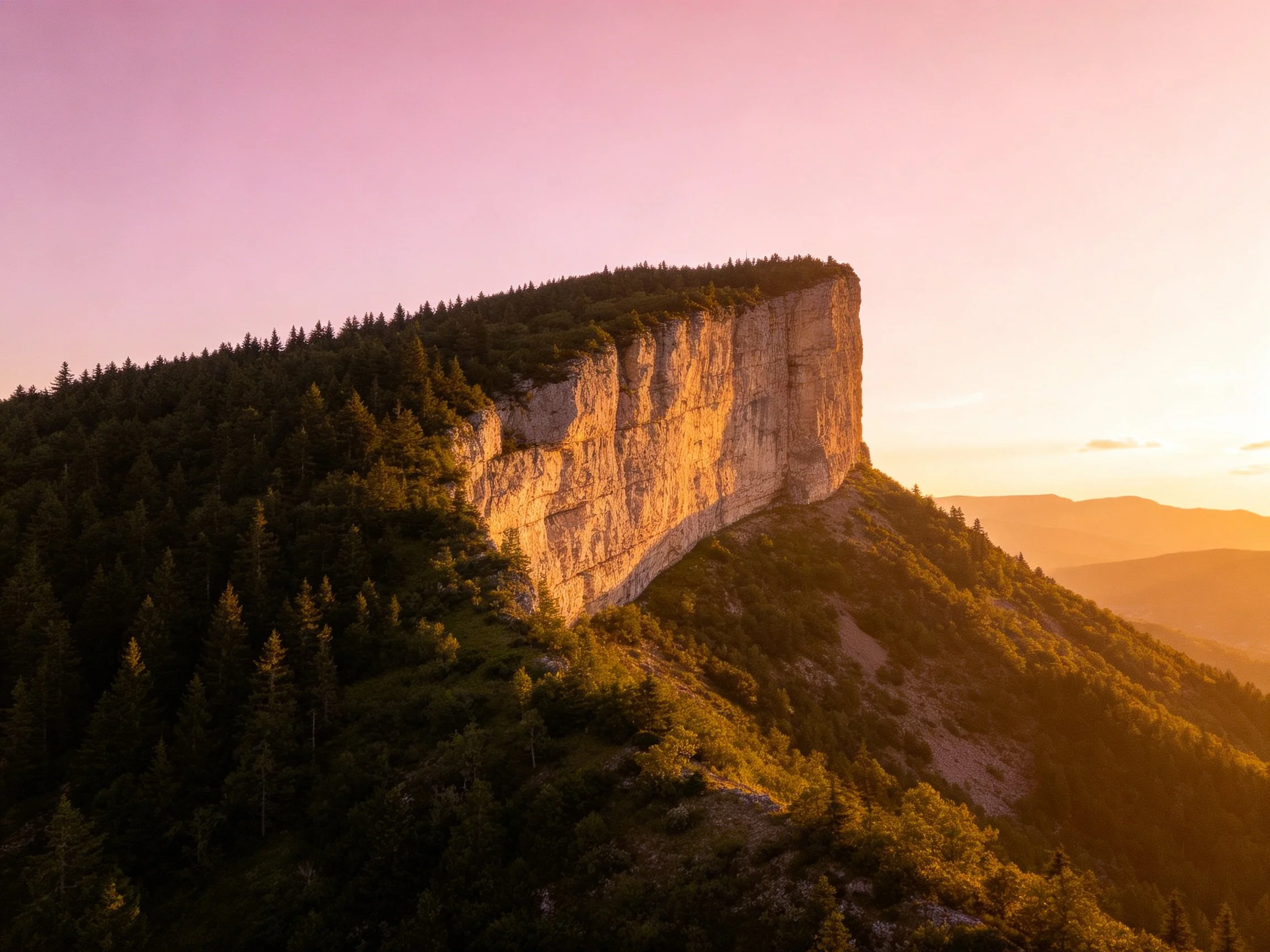 Golden Sunset Highlights a Massive Cliff with Dense Forest