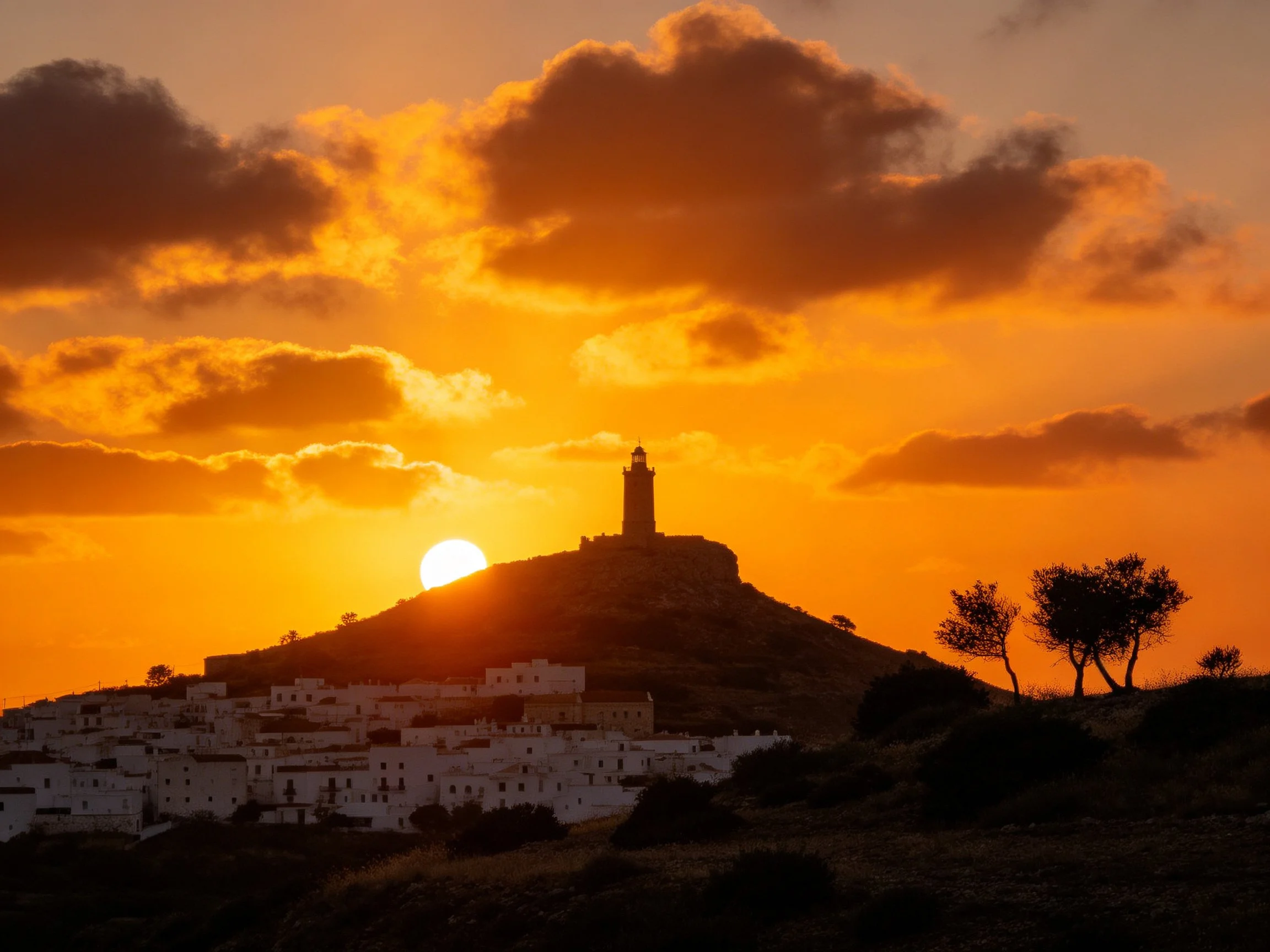 Golden Sunset Illuminates Hilltop Lighthouse and Village