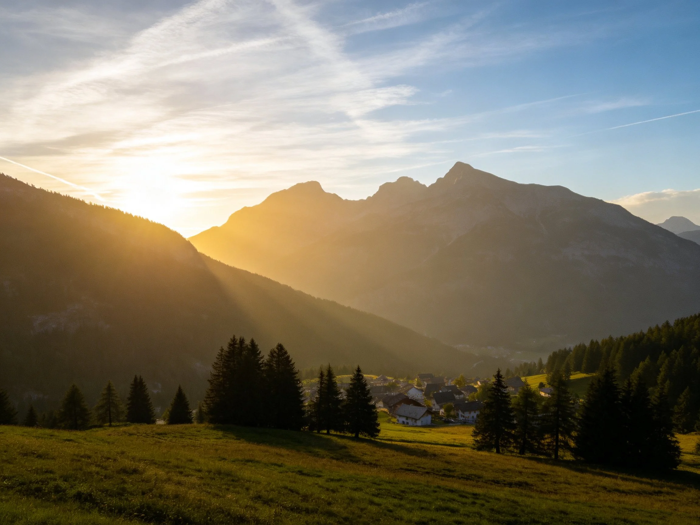 Golden Sunset Over Mountain Peaks With Pine Trees And Village