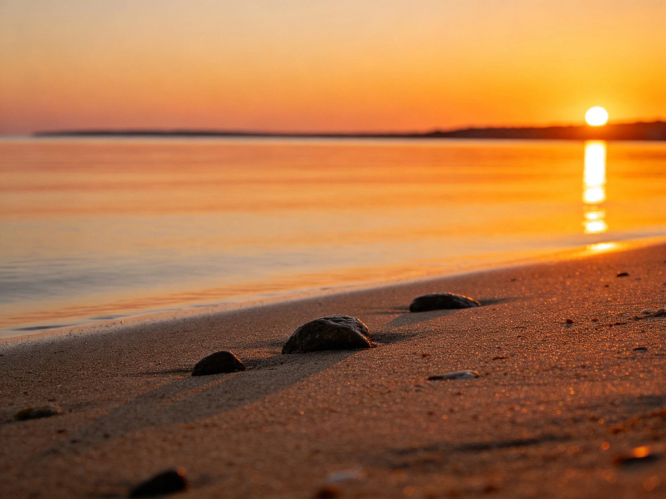 Golden Sunset Over Sandy Beach With Scattered Rocks