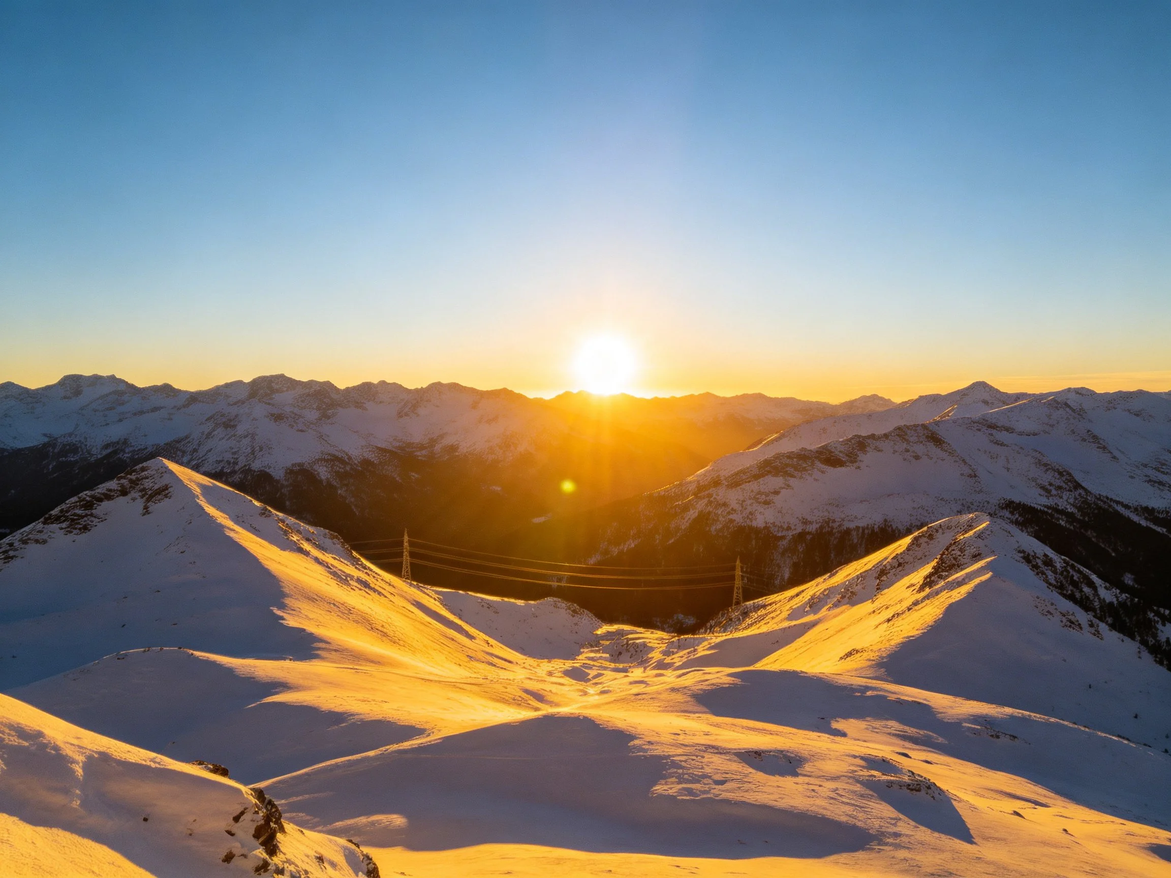 Golden Sunset Over Snow-Covered Mountain Peaks With Blue Sky