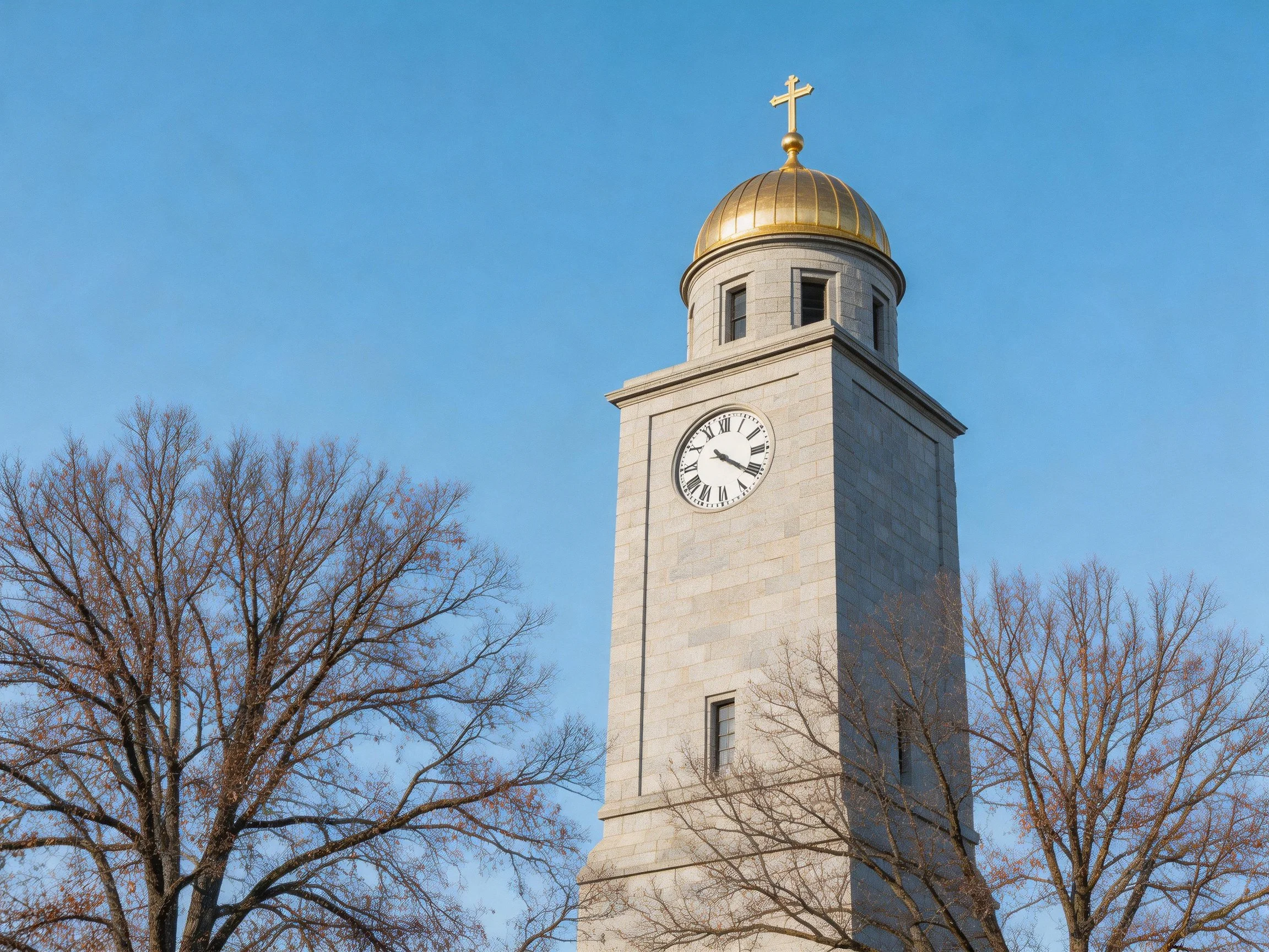 Golden-domed stone clock tower with cross, framed by bare trees