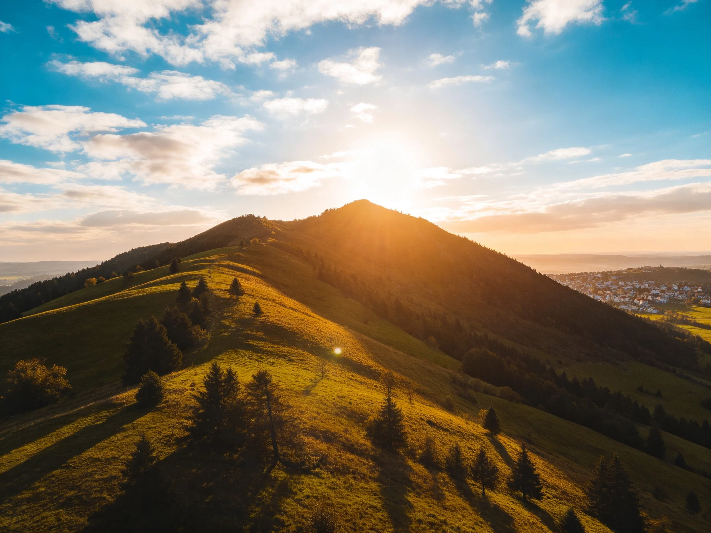 Golden-lit mountain with rolling green slopes and scattered trees