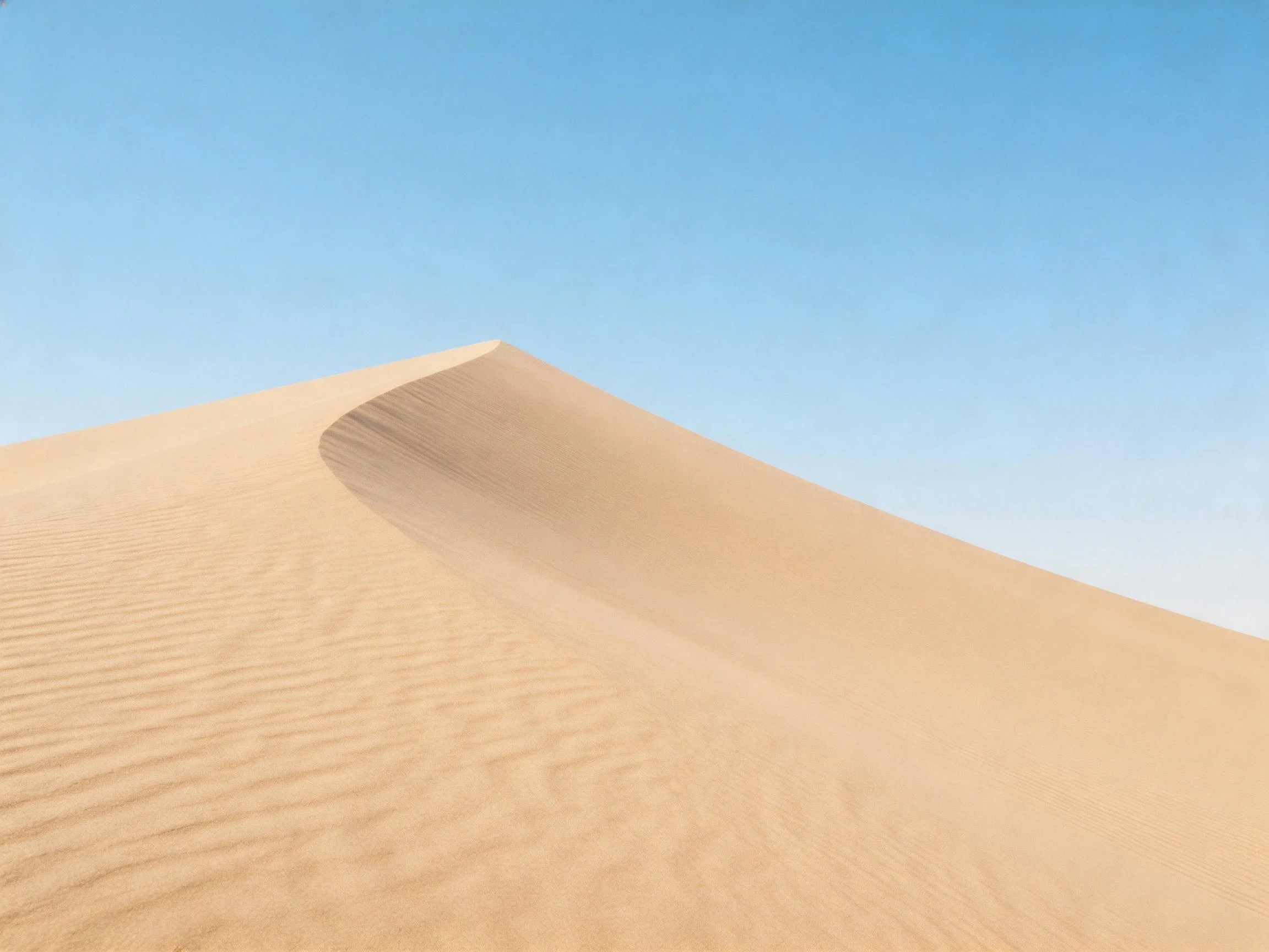 Golden sand dunes with smooth curves under clear blue sky