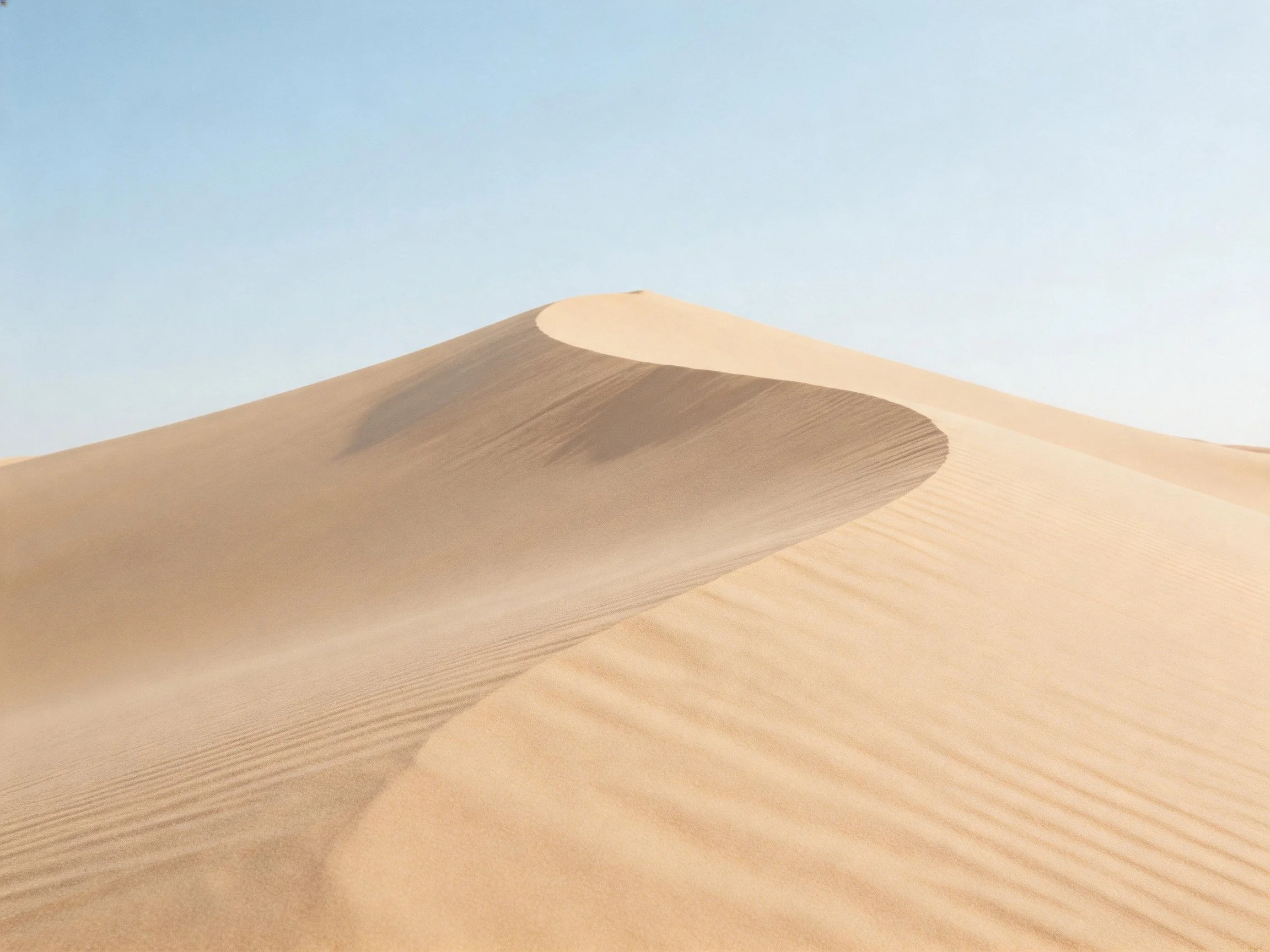 Golden sand dunes with smooth curves under clear blue sky