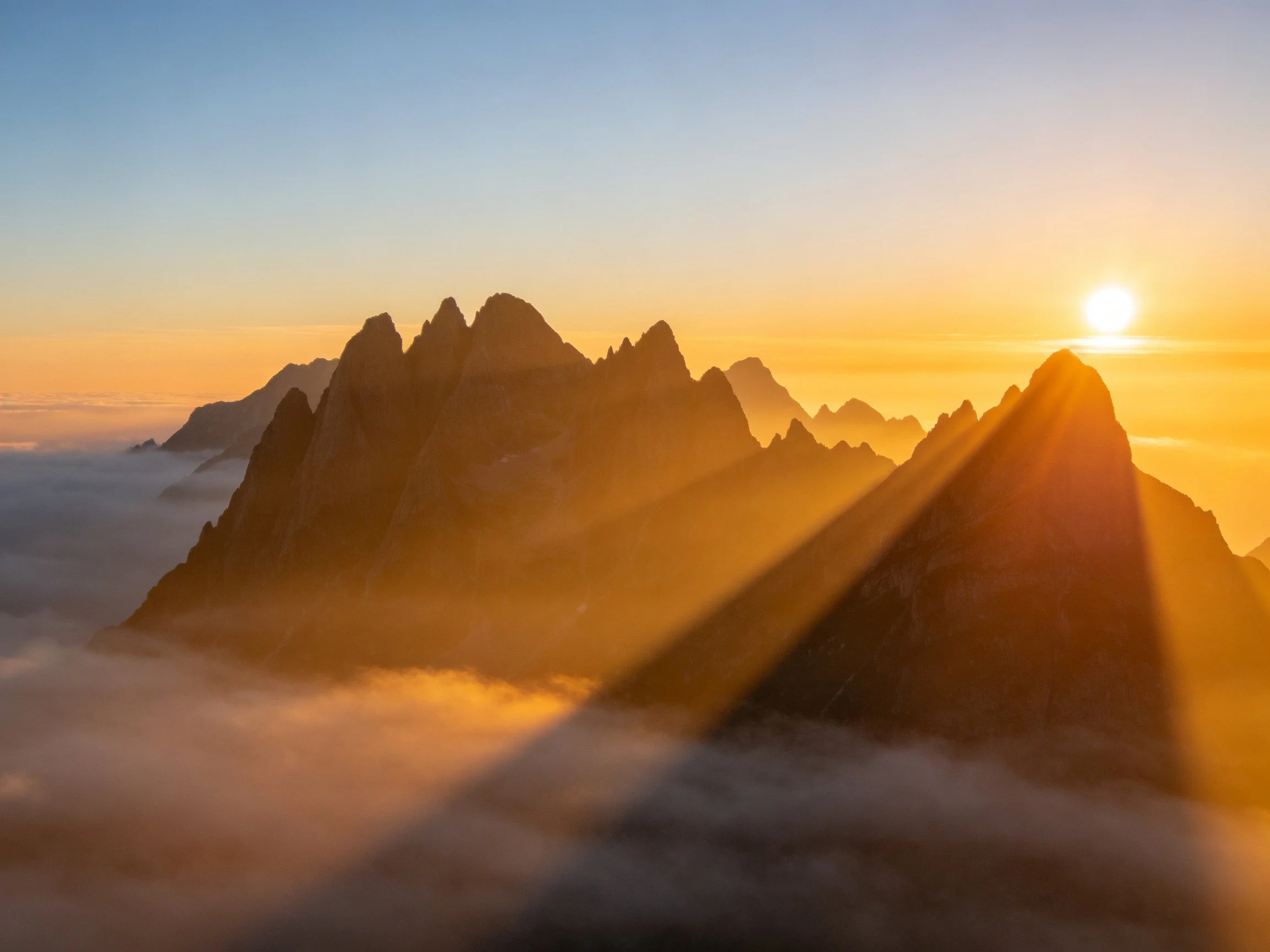 Golden sunrise illuminates jagged mountain peaks