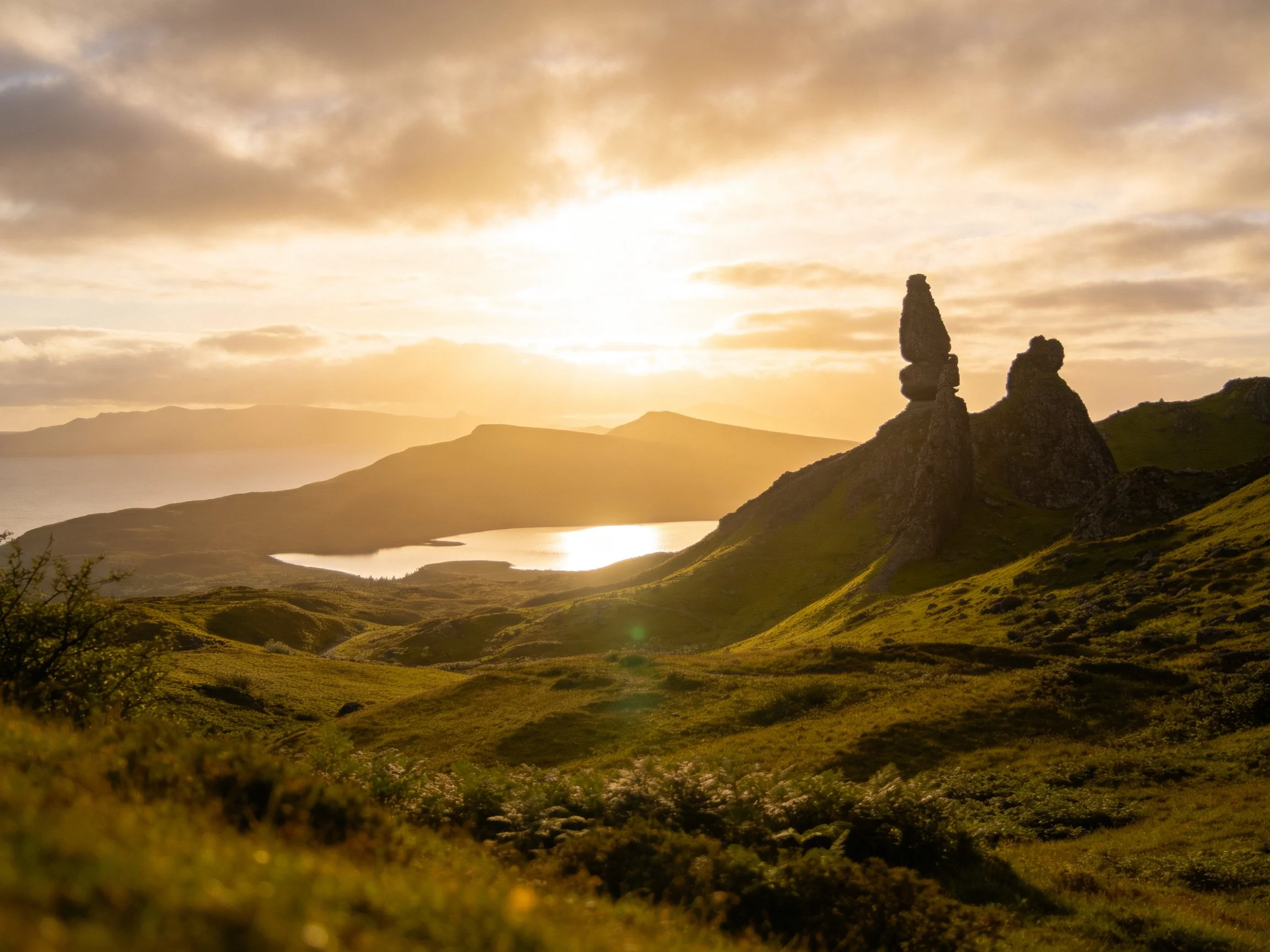 Golden sunset illuminates ancient rock formations near tranquil lake