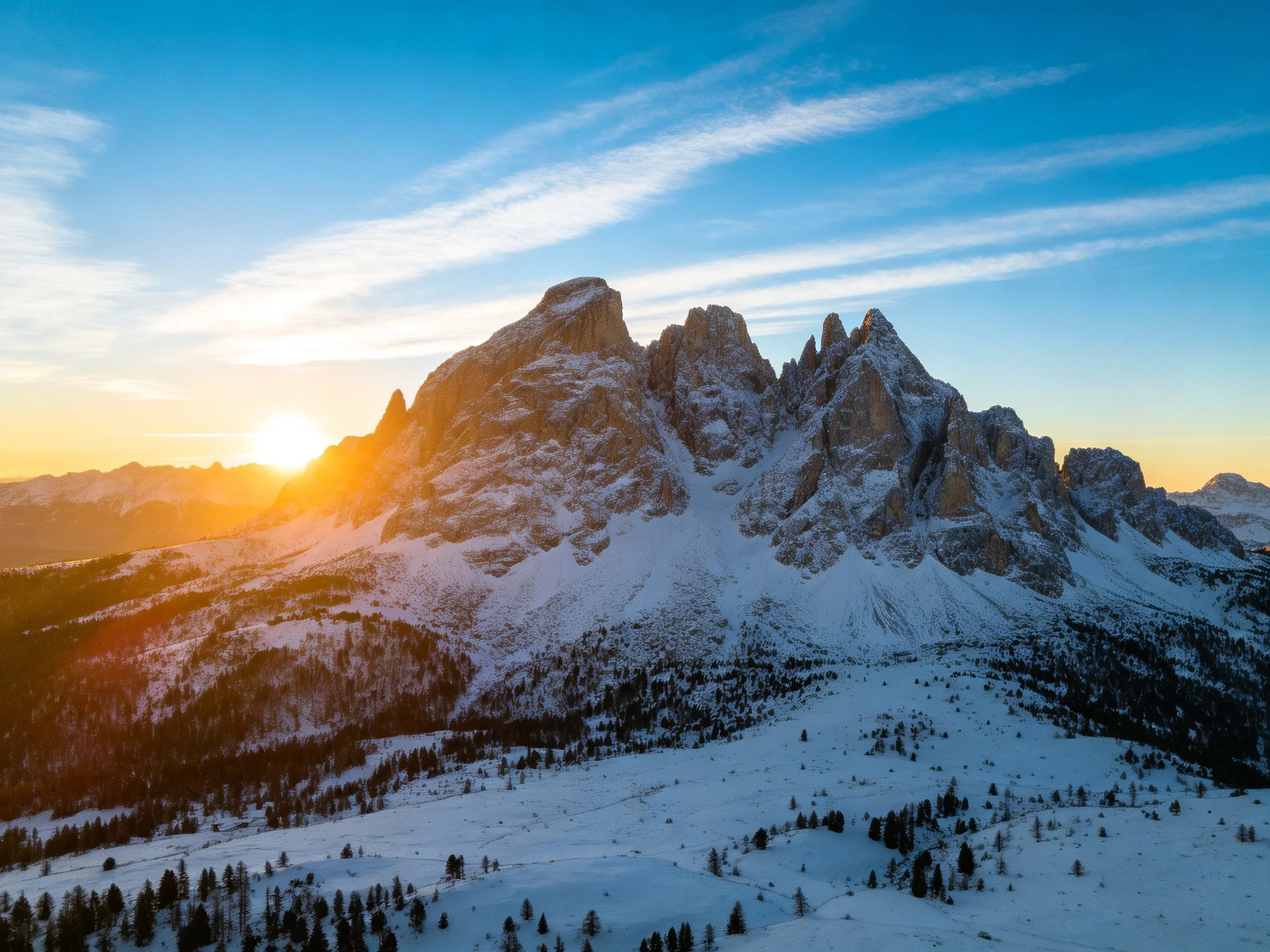 Golden sunset illuminates snow - capped mountain peaks.