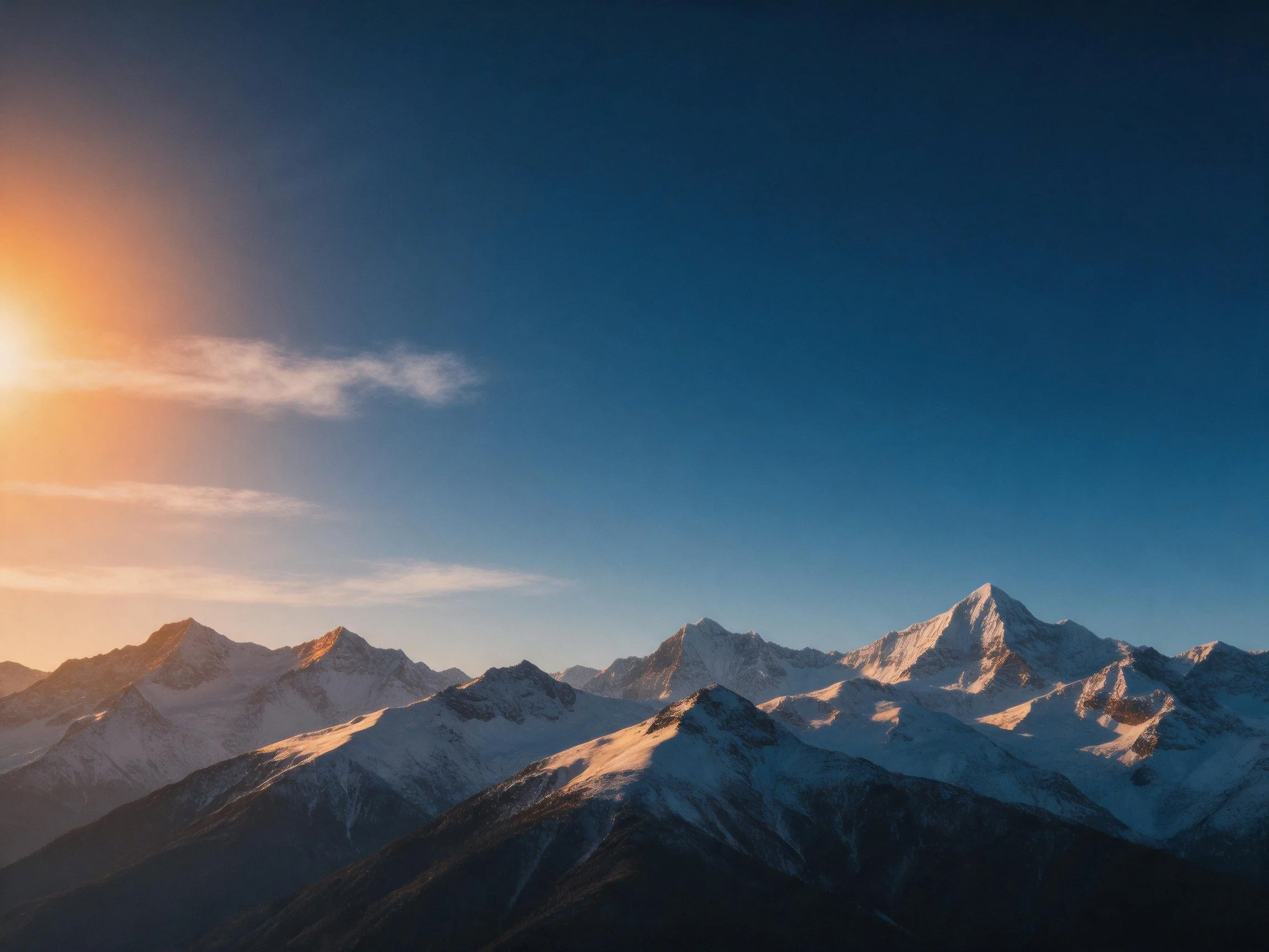 Golden sunset illuminates snow - capped mountain ranges against a deep blue sky.