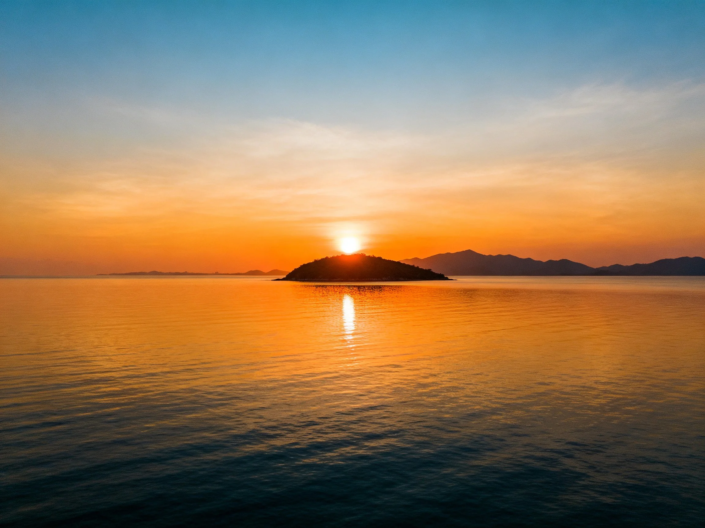 Golden sunset over a central island with calm waters