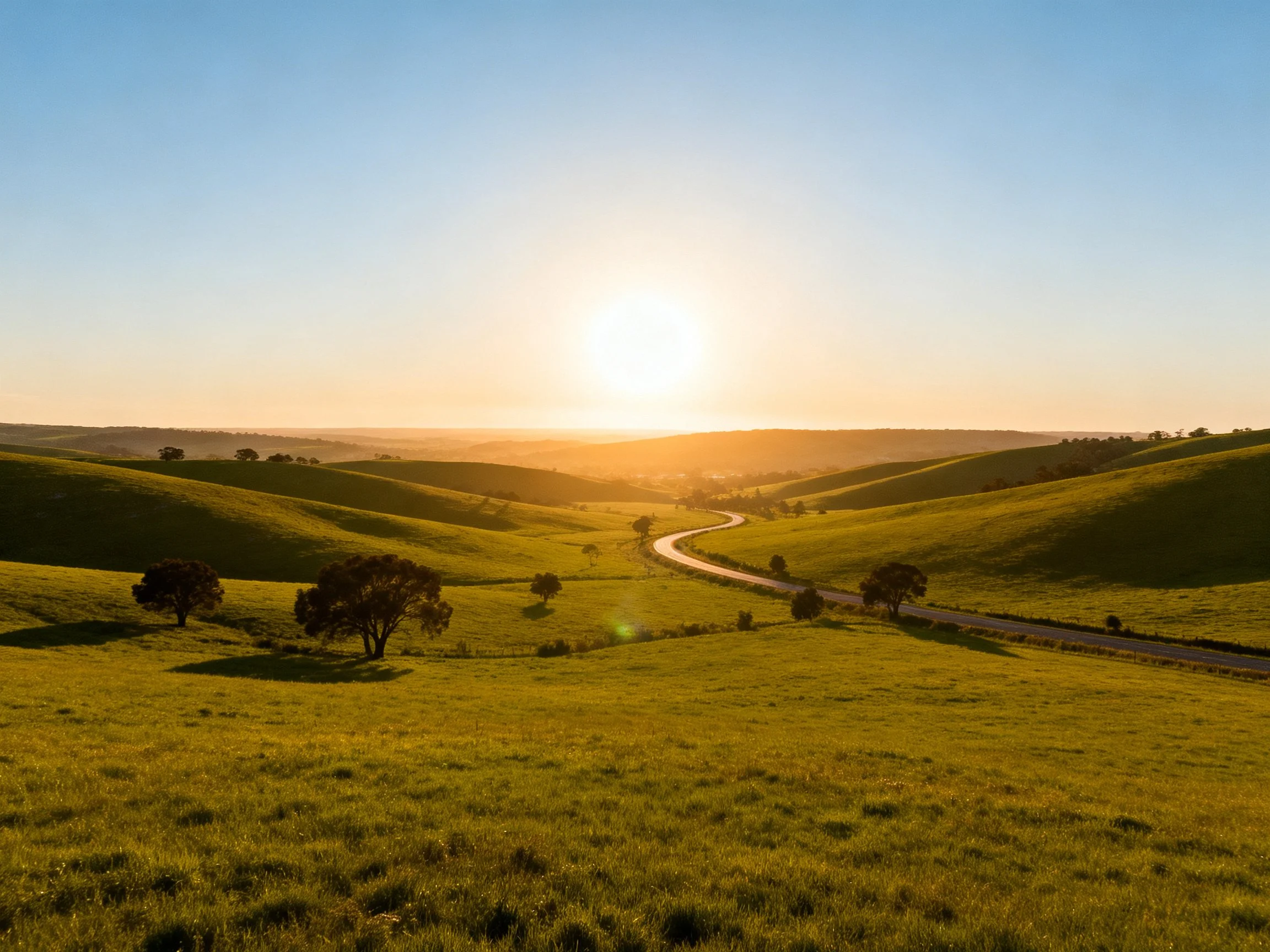Golden sunset over rolling green hills and winding road