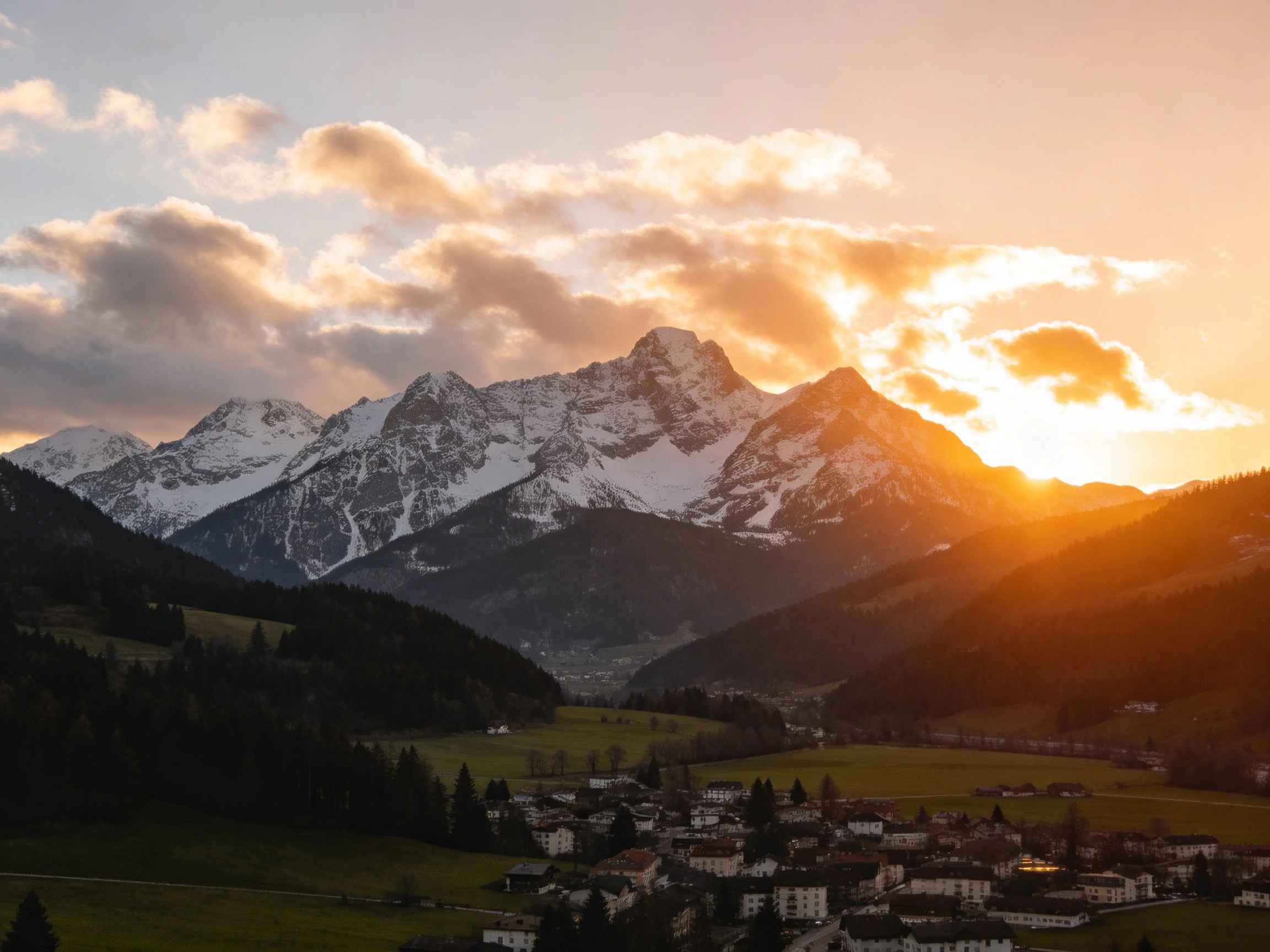 Golden sunset over snow-capped mountain peaks and village valley