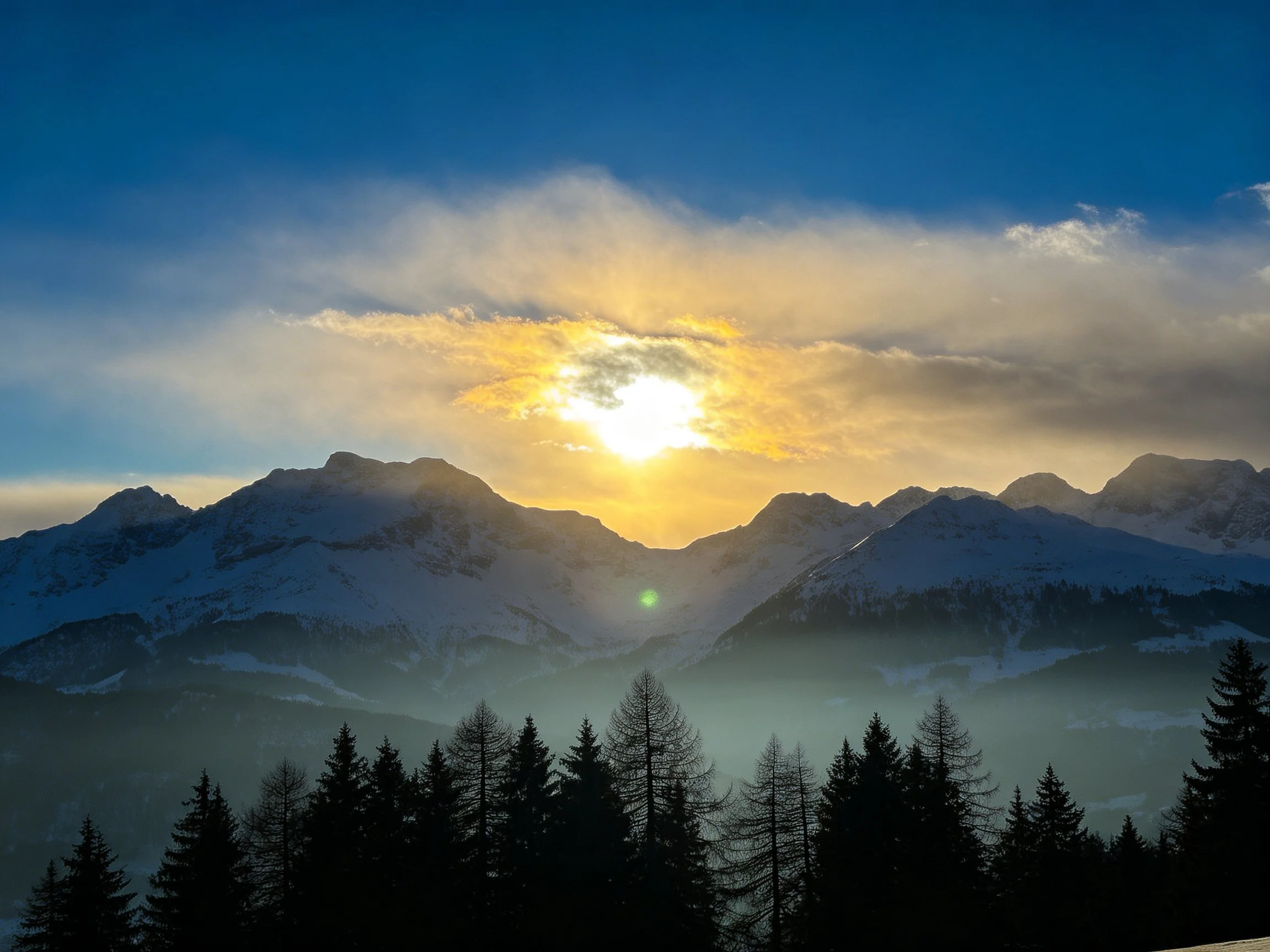 Golden sunset over snow - capped mountain range with blue sky
