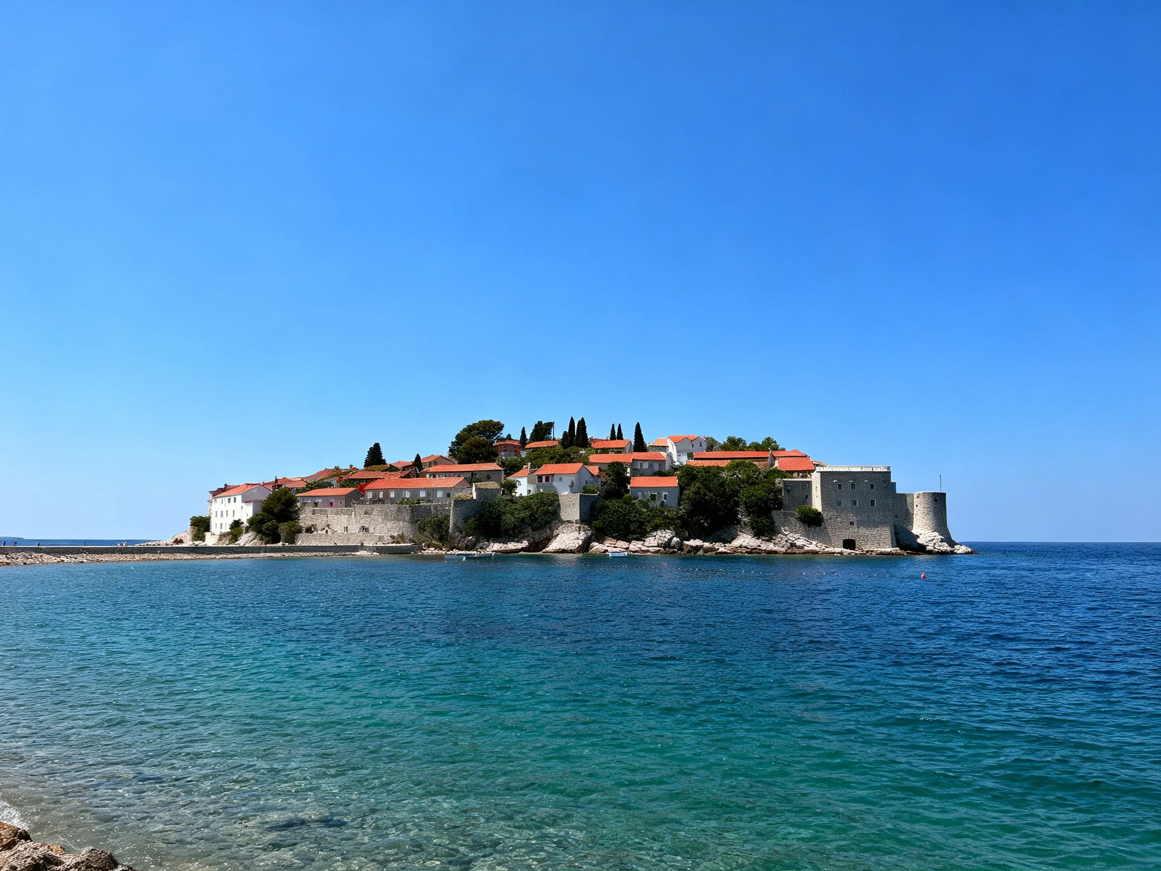 Historic island village with red roofs by turquoise seas