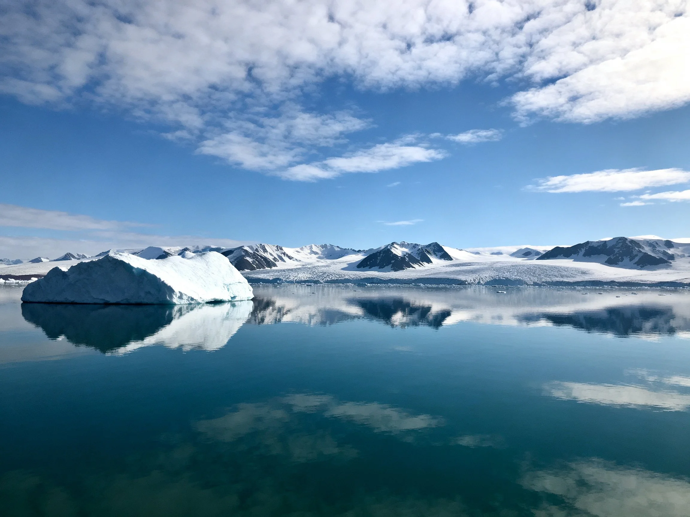 Iceberg in Calm Arctic Waters Near Snow-Capped Mountains