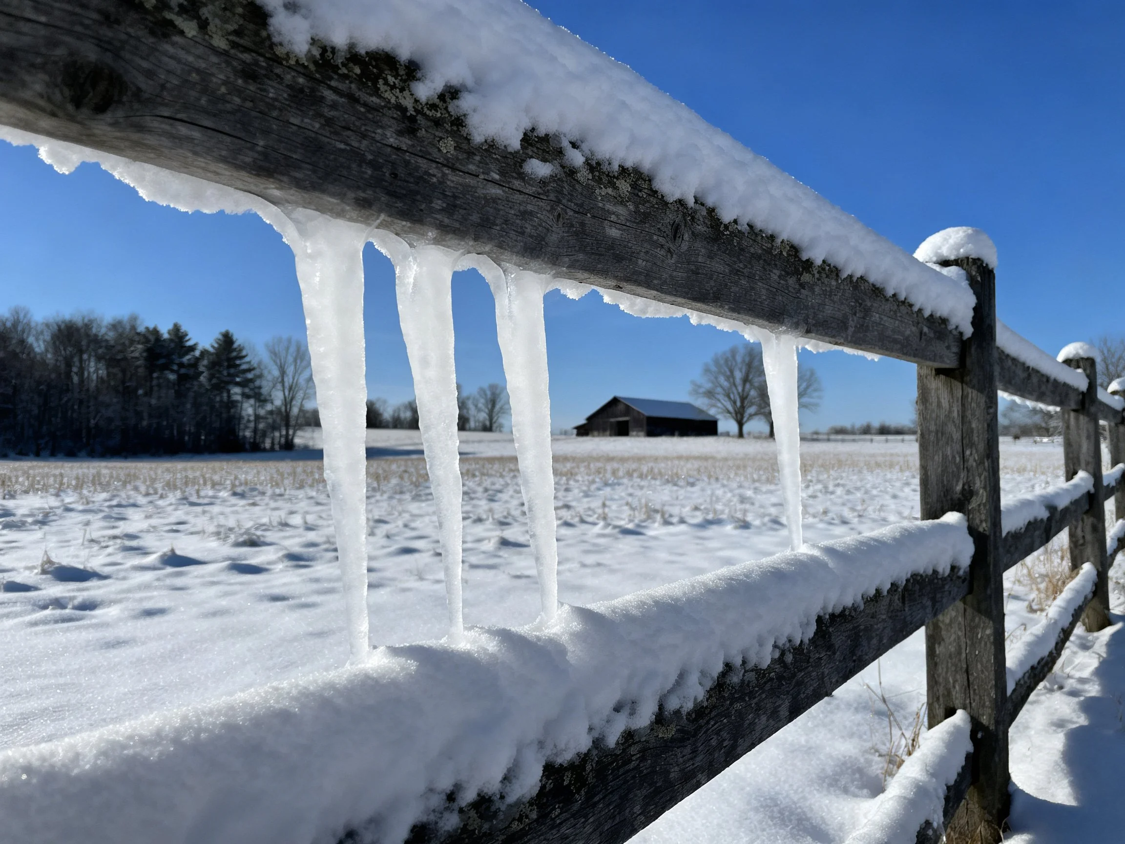 Icy Wooden Fence with Icicles Overlooking Snow-Covered Field