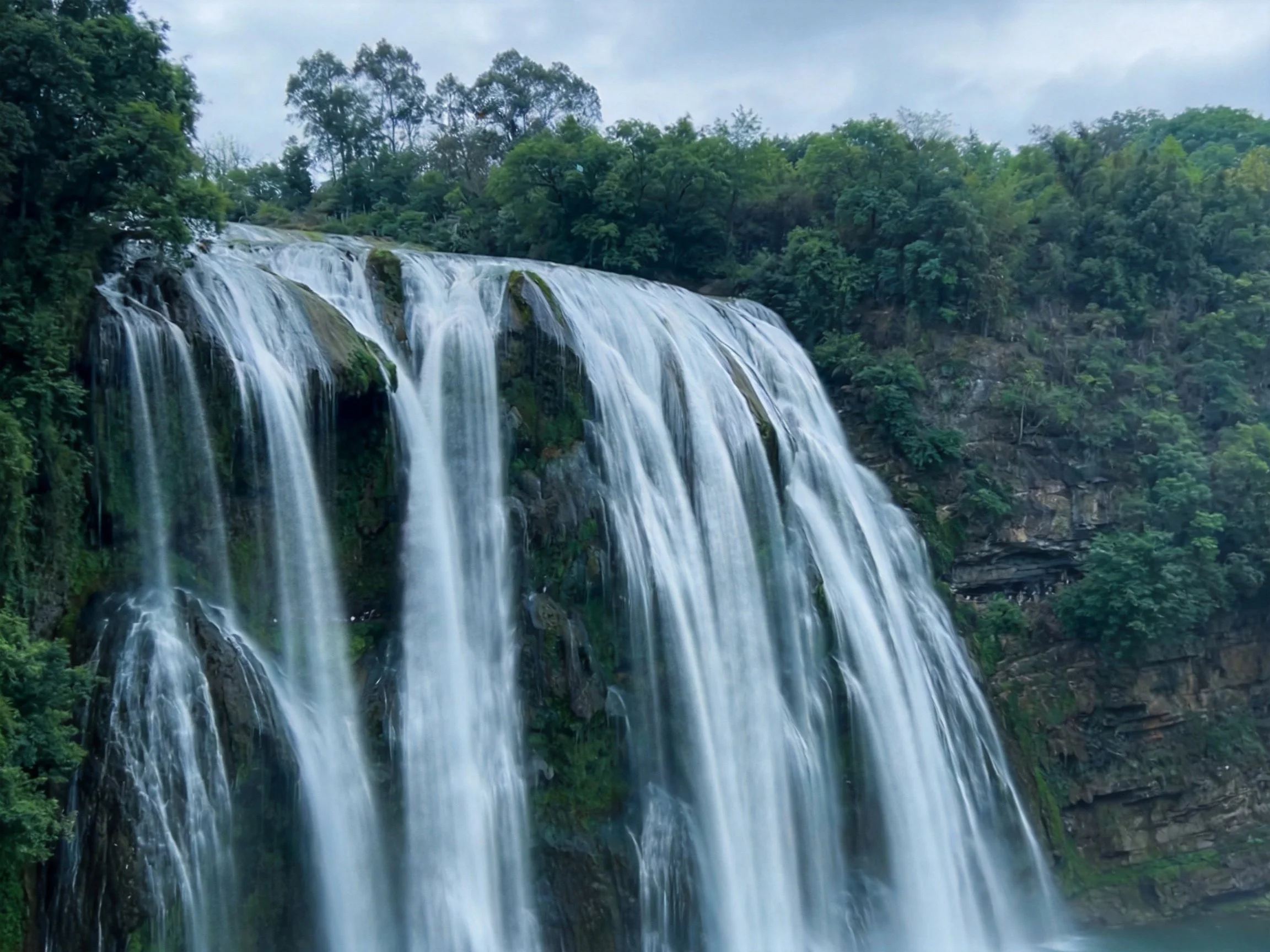 Large waterfall with white foamy water and green surroundings
