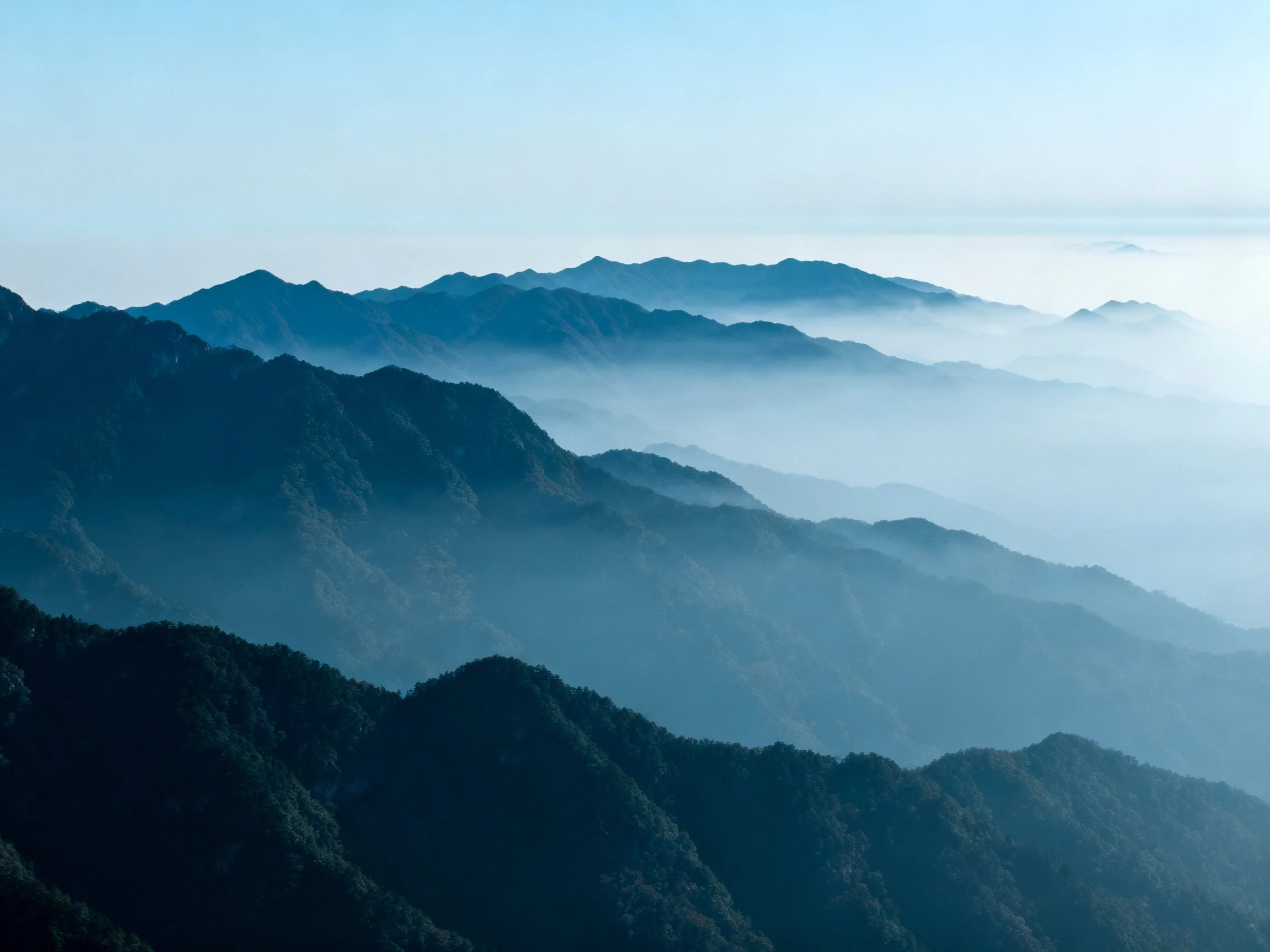 Layered mountain ridges shrouded in misty blue haze