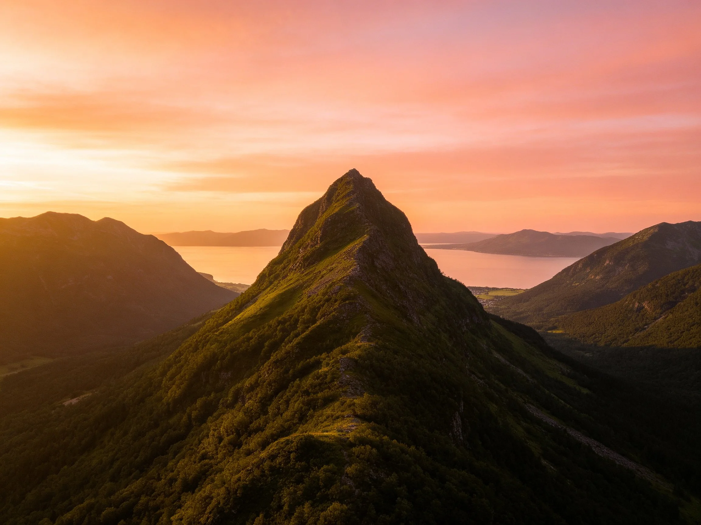 Lush green mountain peak under vibrant sunset skies