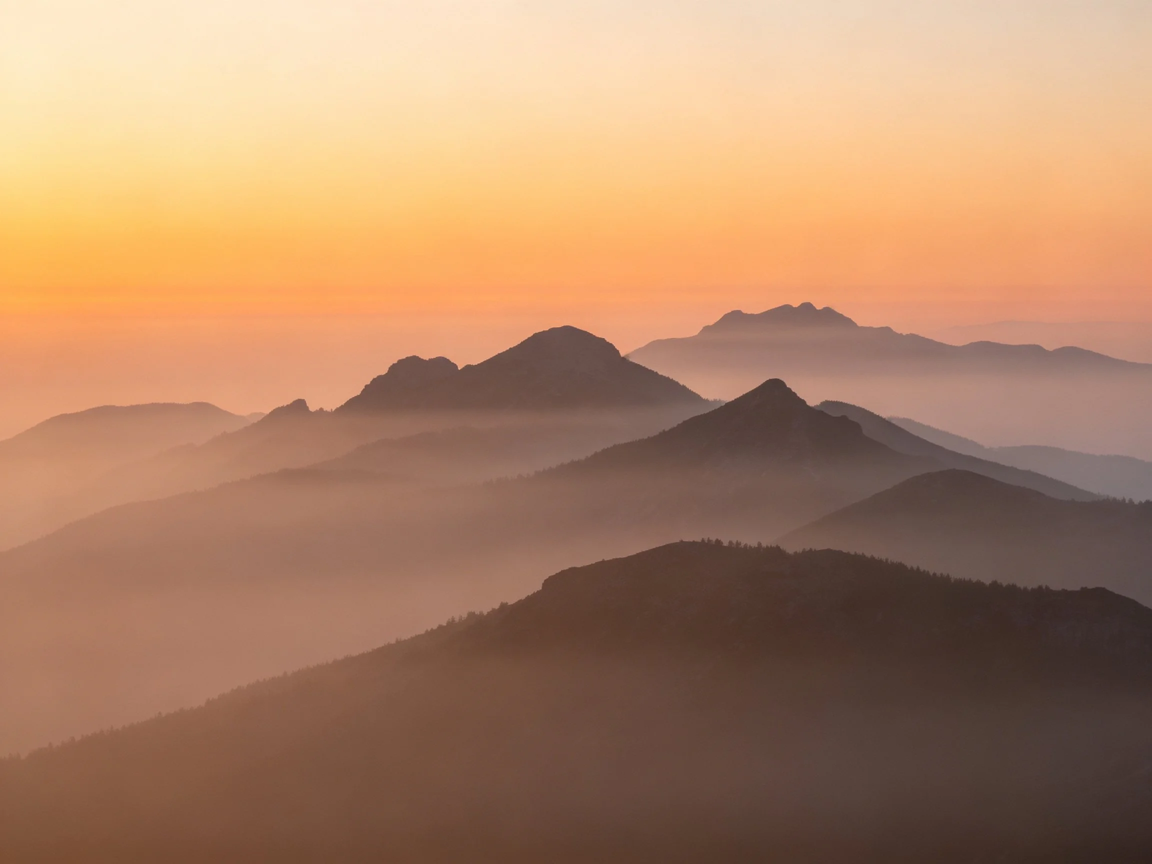 Misty Mountain Peaks at Dawn with Layered Silhouettes
