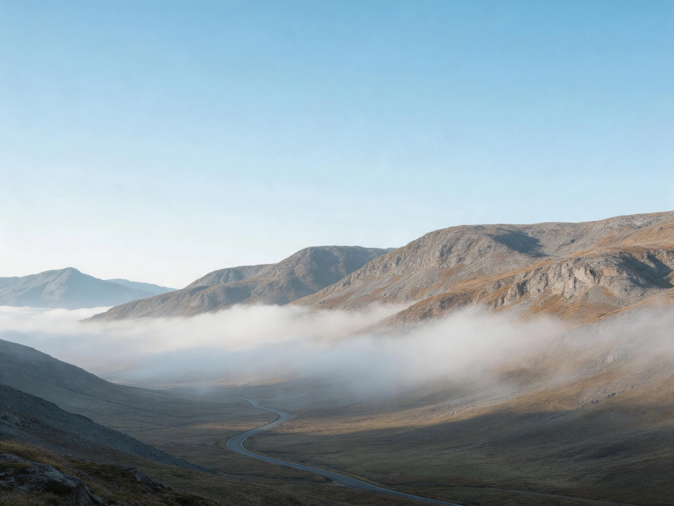 Misty Mountain Valley with Winding Road Under Clear Sky
