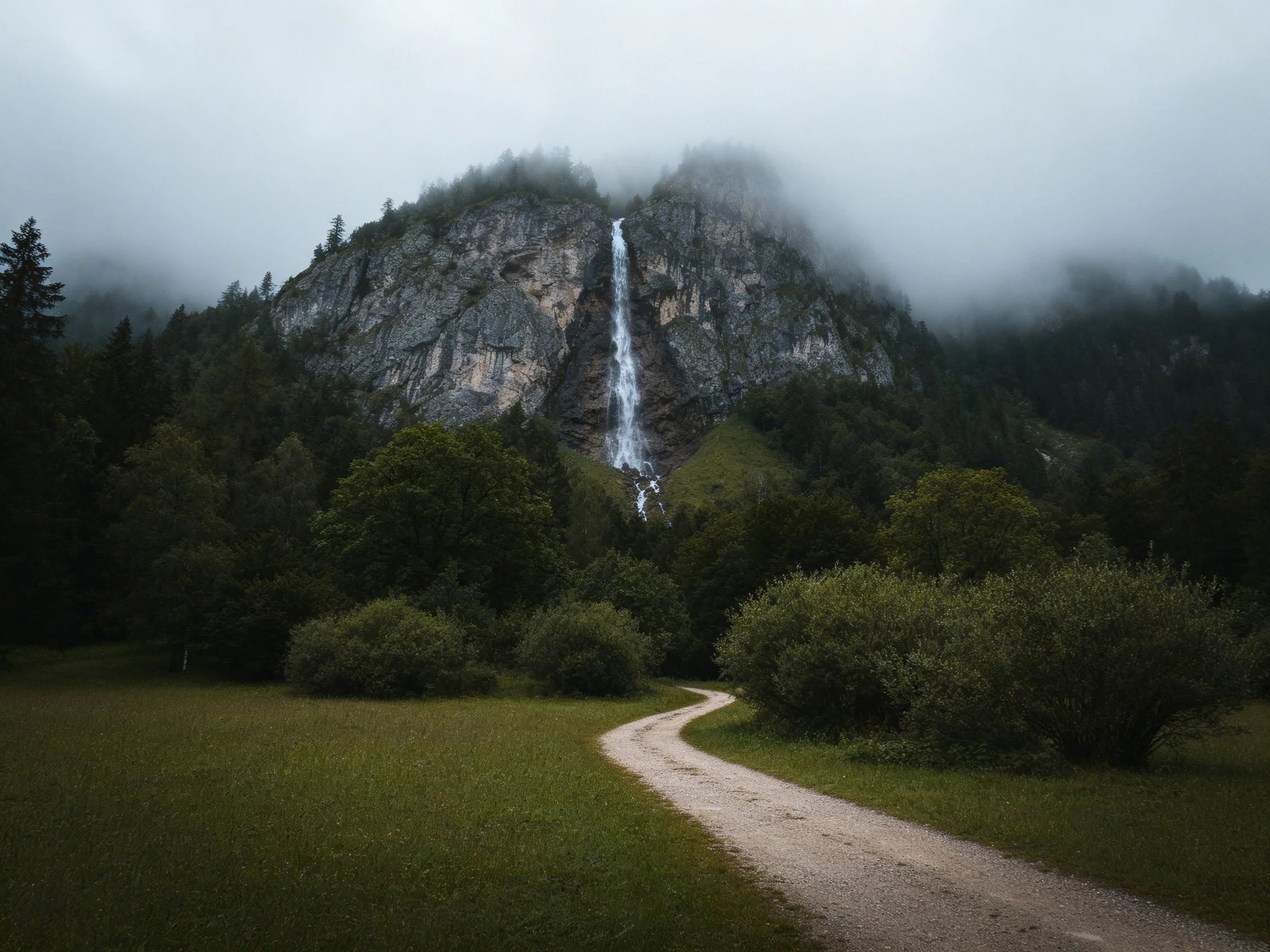 Misty Mountain Waterfall with Lush Greenery and Winding Path