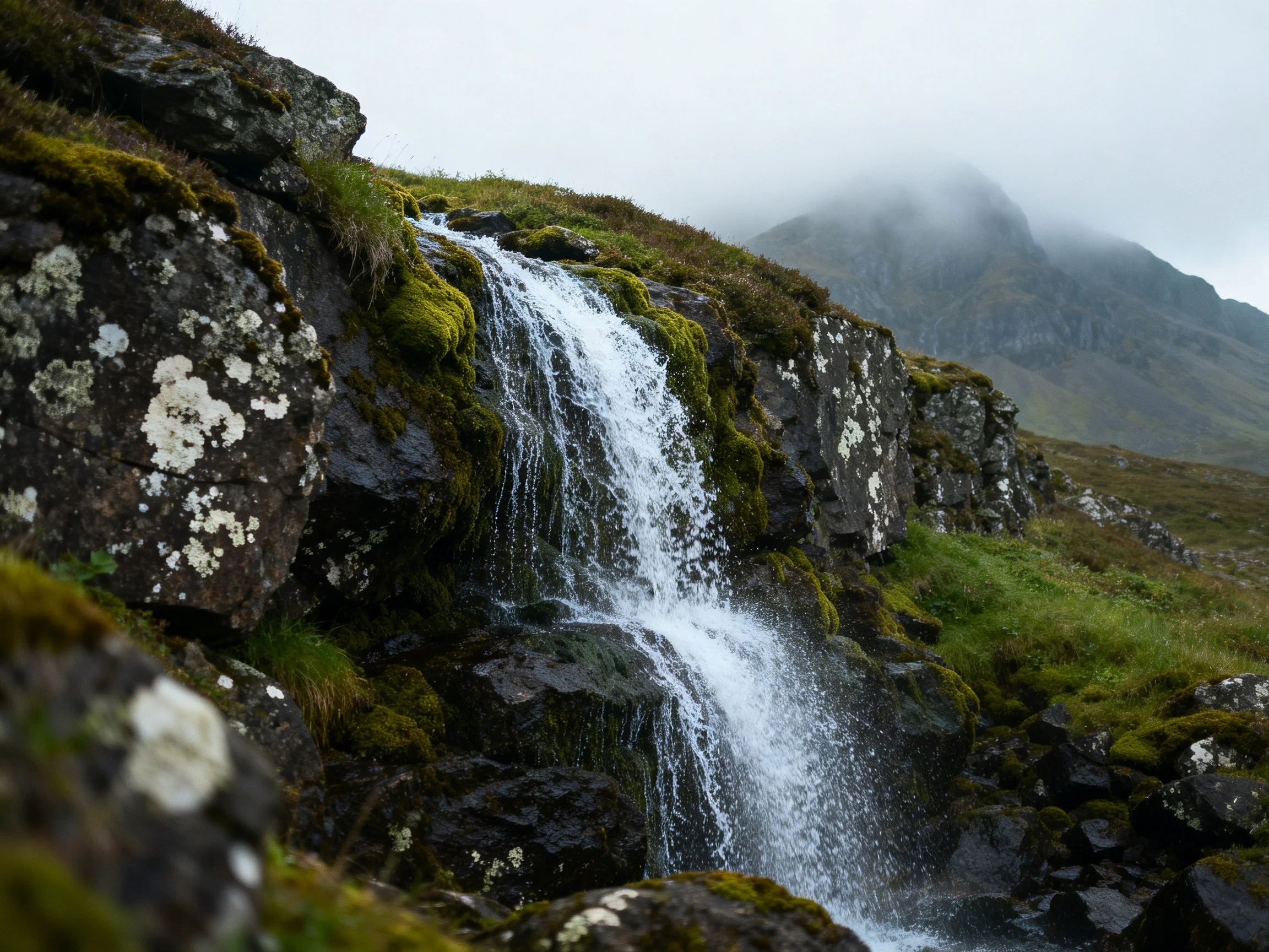 Moss-Covered Rocks With Flowing Waterfall and Misty Mountain