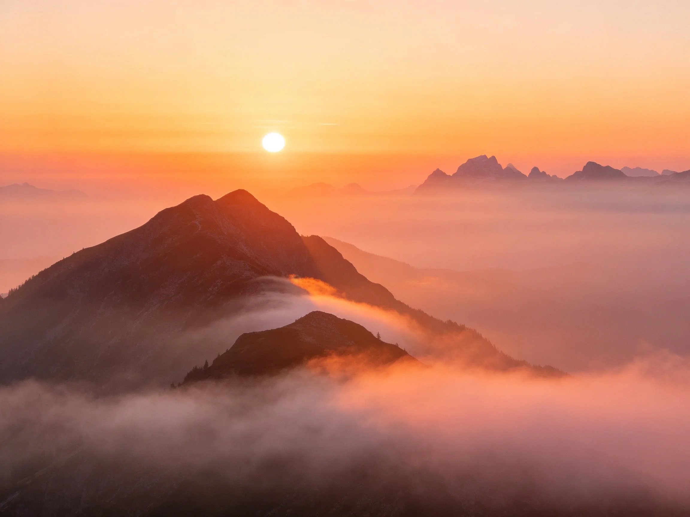 Mountain Peaks at Sunrise with Golden Light and Misty Clouds