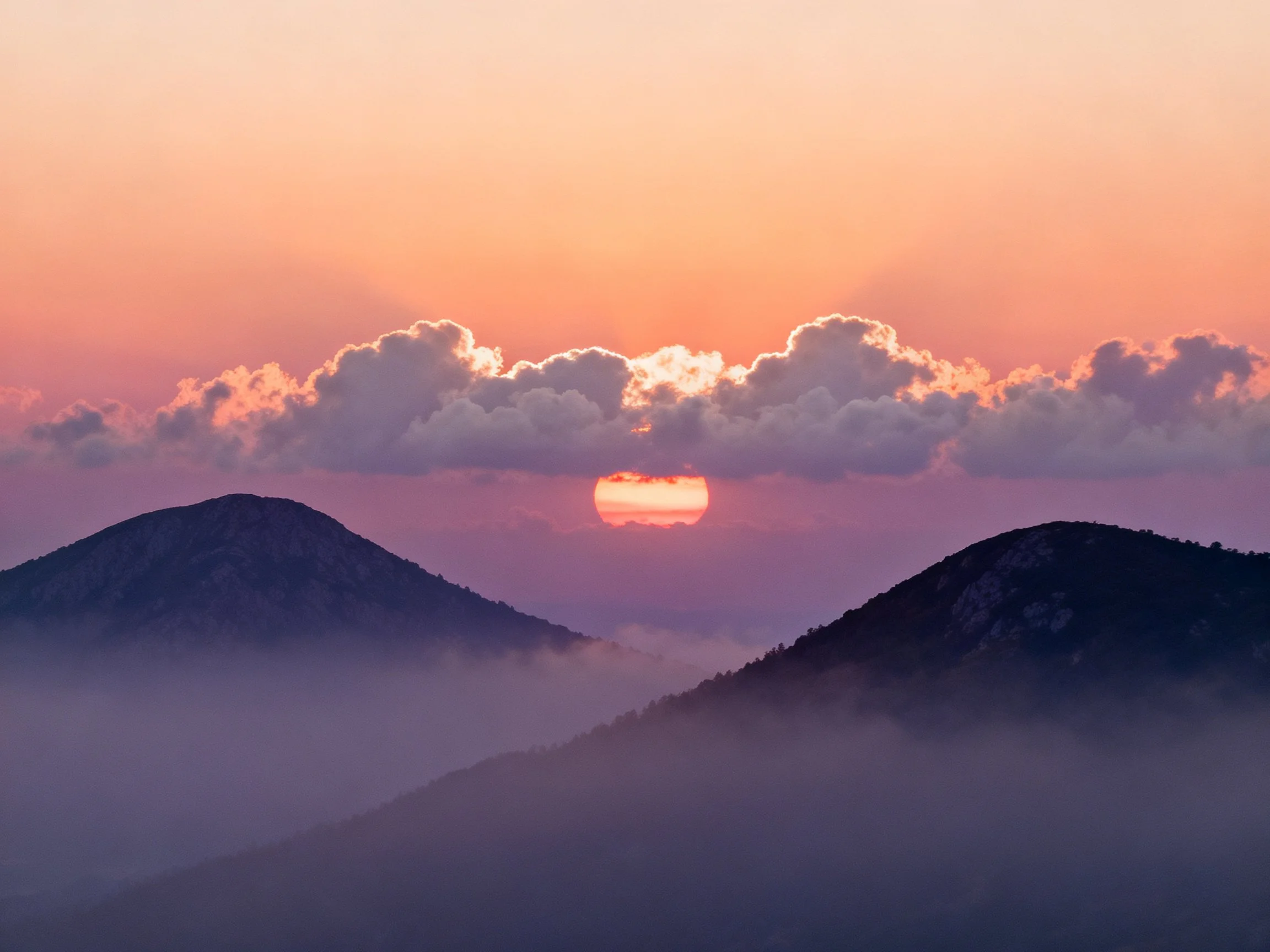 Mountain Peaks at Sunset with Cloudy Sky and Mist
