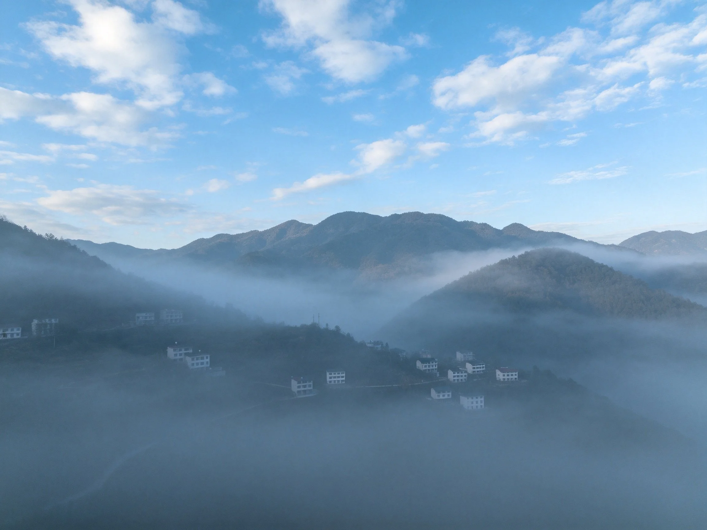 Mountain Village Shrouded in Morning Mist Under Blue Sky