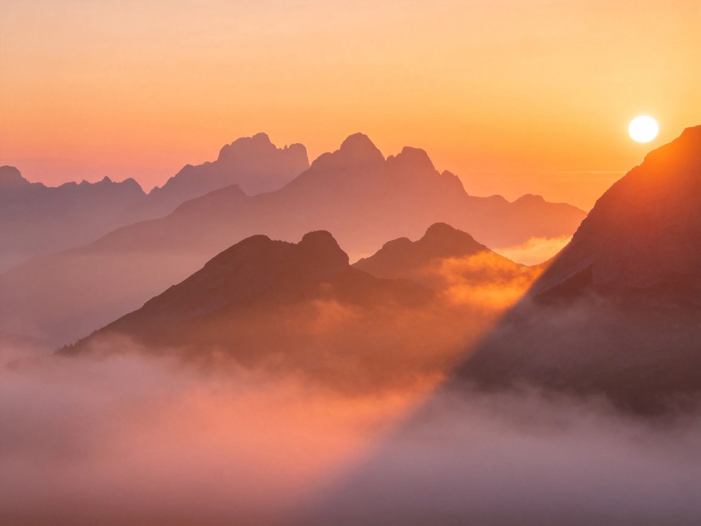 Mountain peaks glowing with golden sunset light amid misty valleys