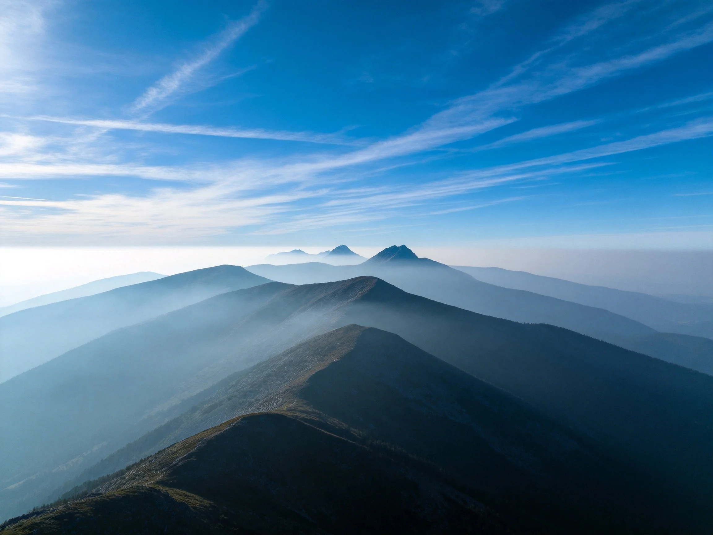 Mountain ridges layered in misty blue and green hues