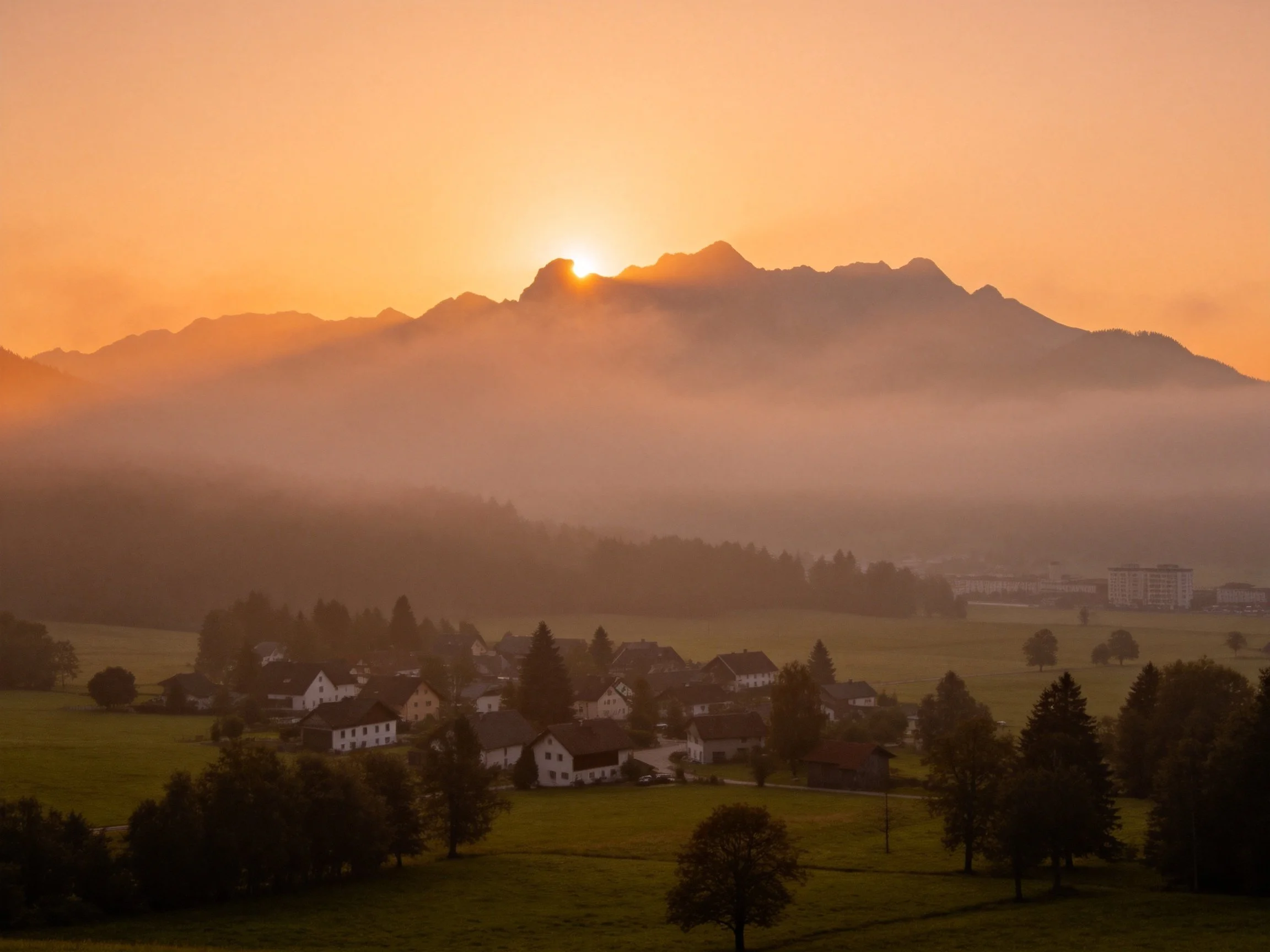 Mountain village enveloped in morning mist under golden sunrise