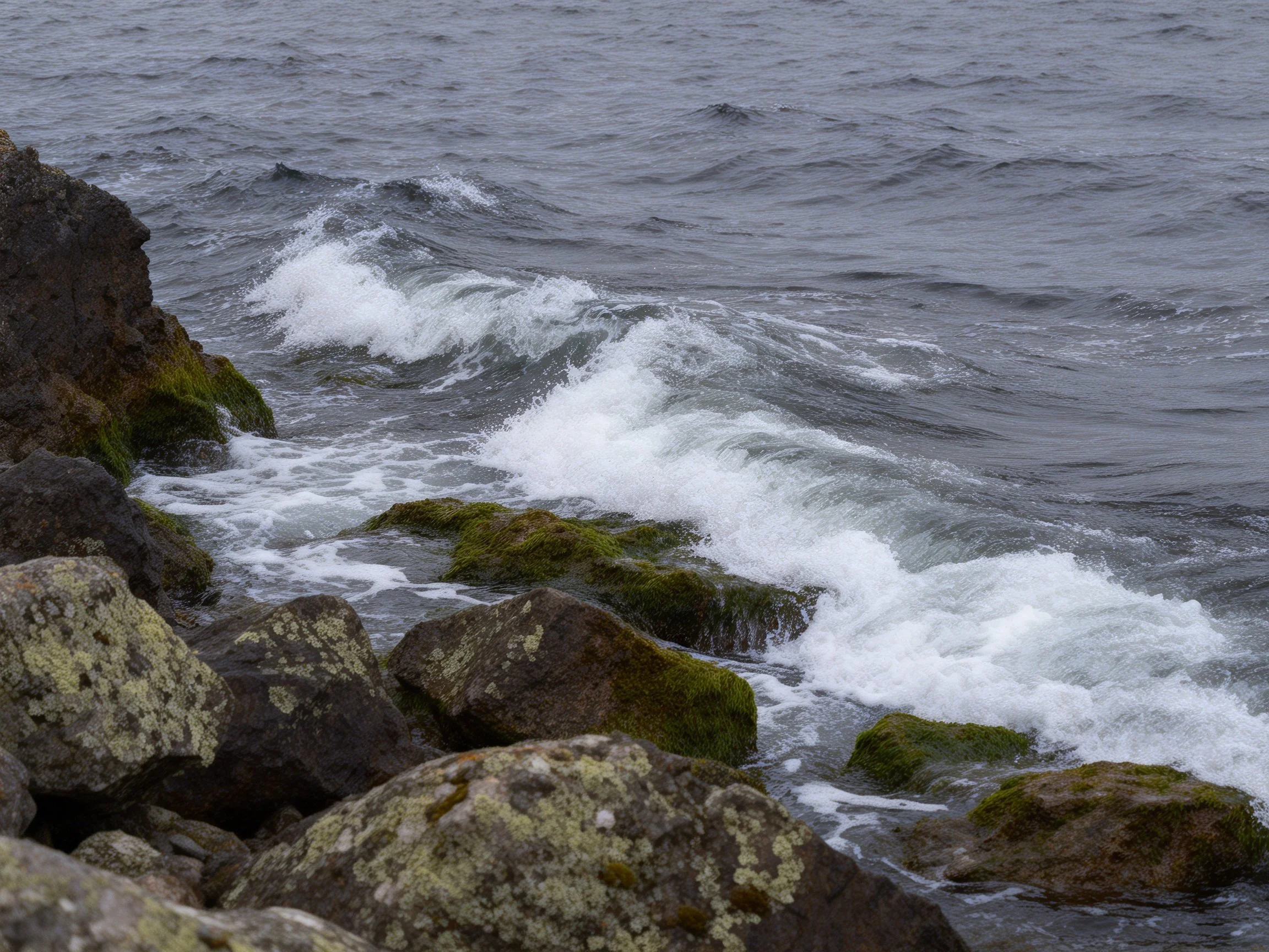 Ocean Waves Crashing Against Moss-Covered Coastal Rocks