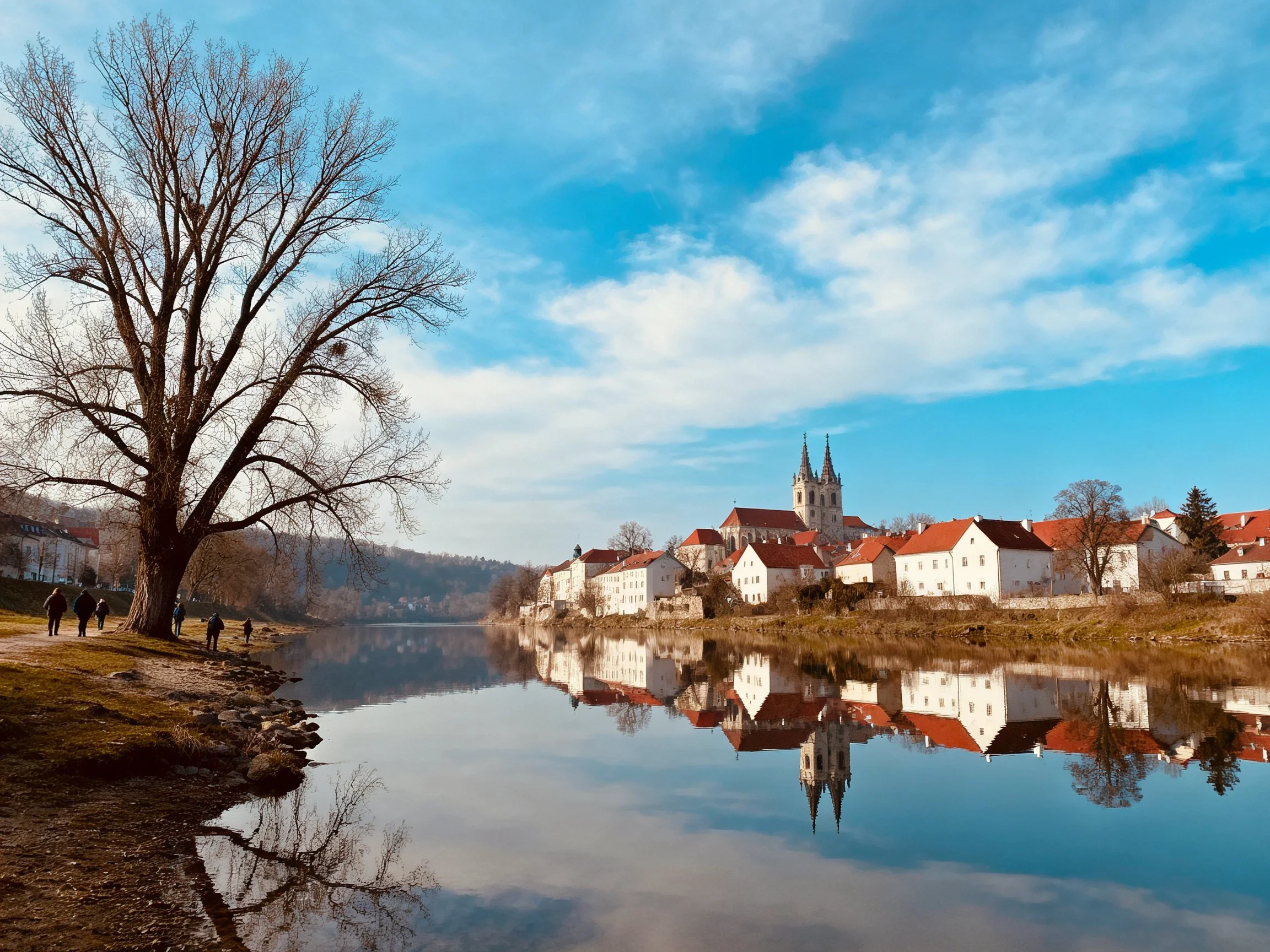 Red-roofed village reflected in tranquil river waters