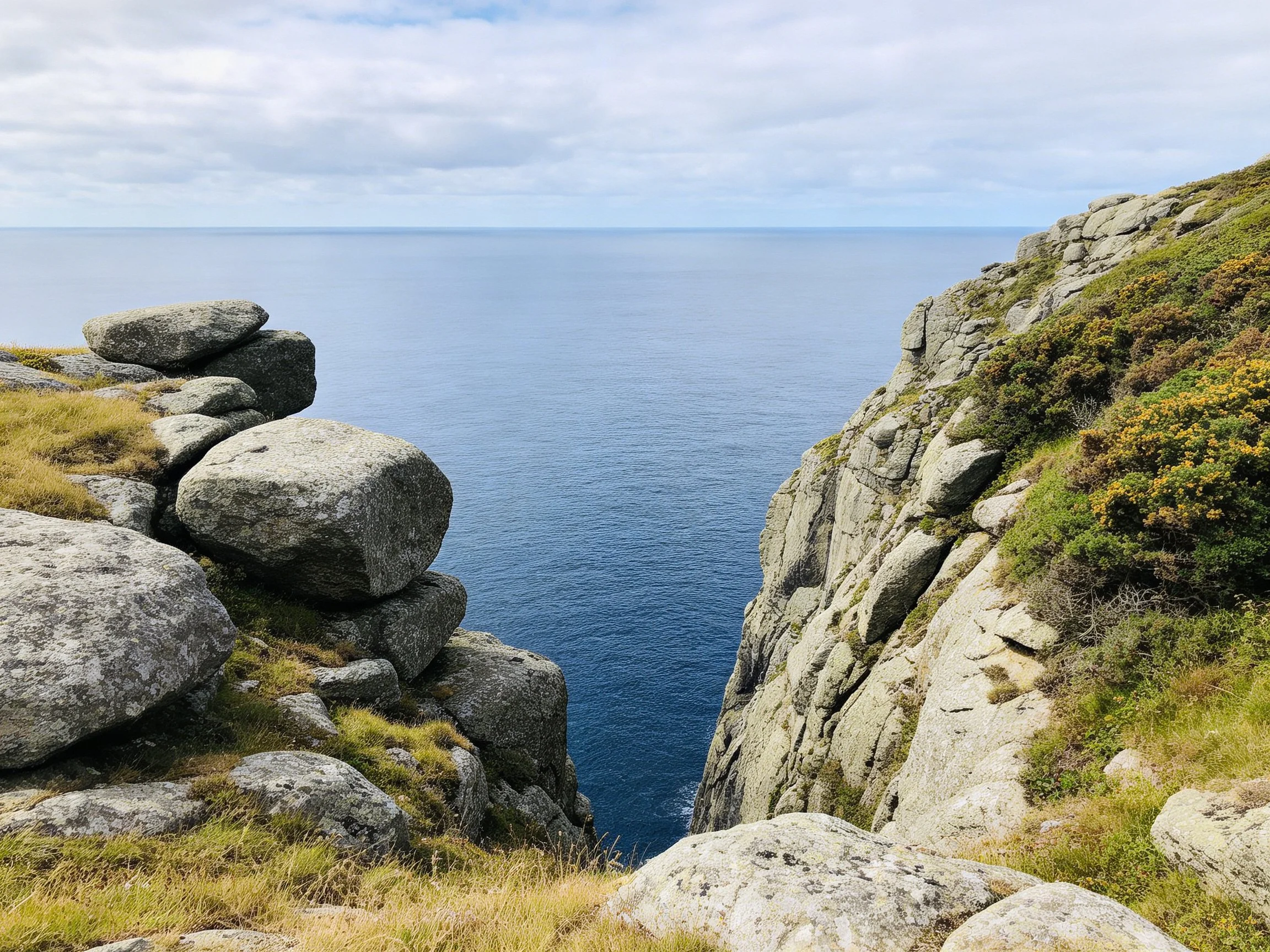 Rocky Coastal Cliffs With Boulders Over Deep Blue Ocean