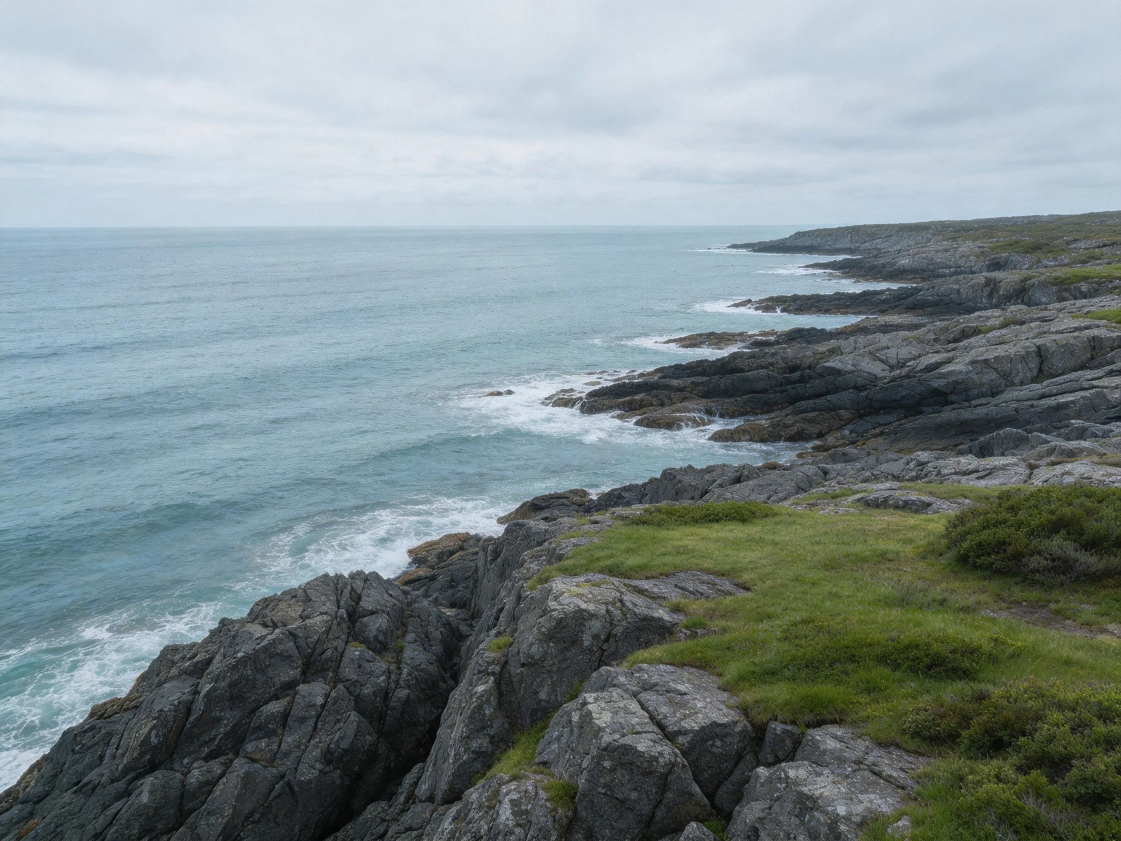 Rocky coastal cliffs border turquoise waters with green vegetation under an overcast sky