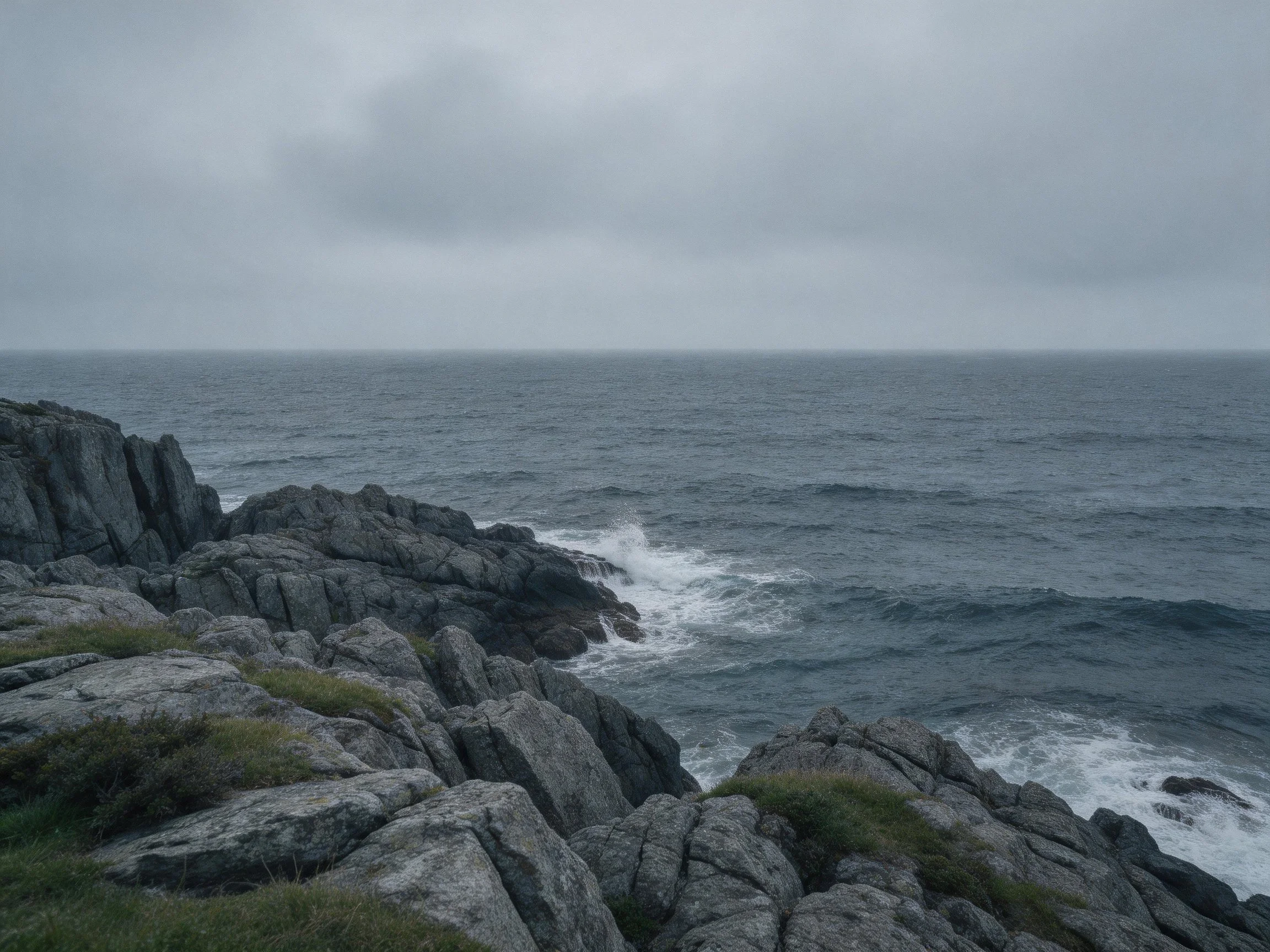 Rocky shoreline with jagged stones and turbulent sea under gray sky