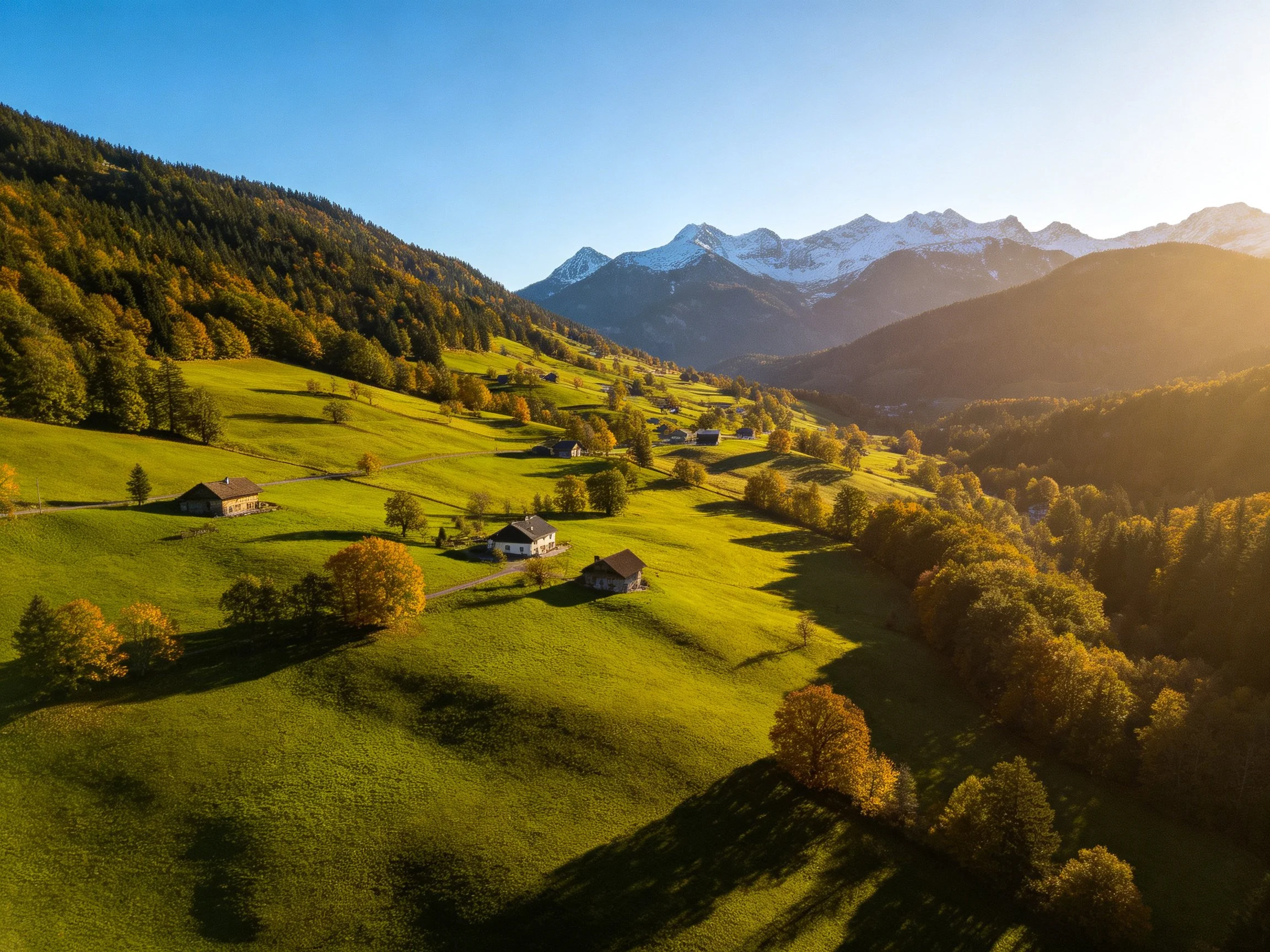 Rolling green hills, scattered cottages, and snow-capped mountains bathed in golden light.