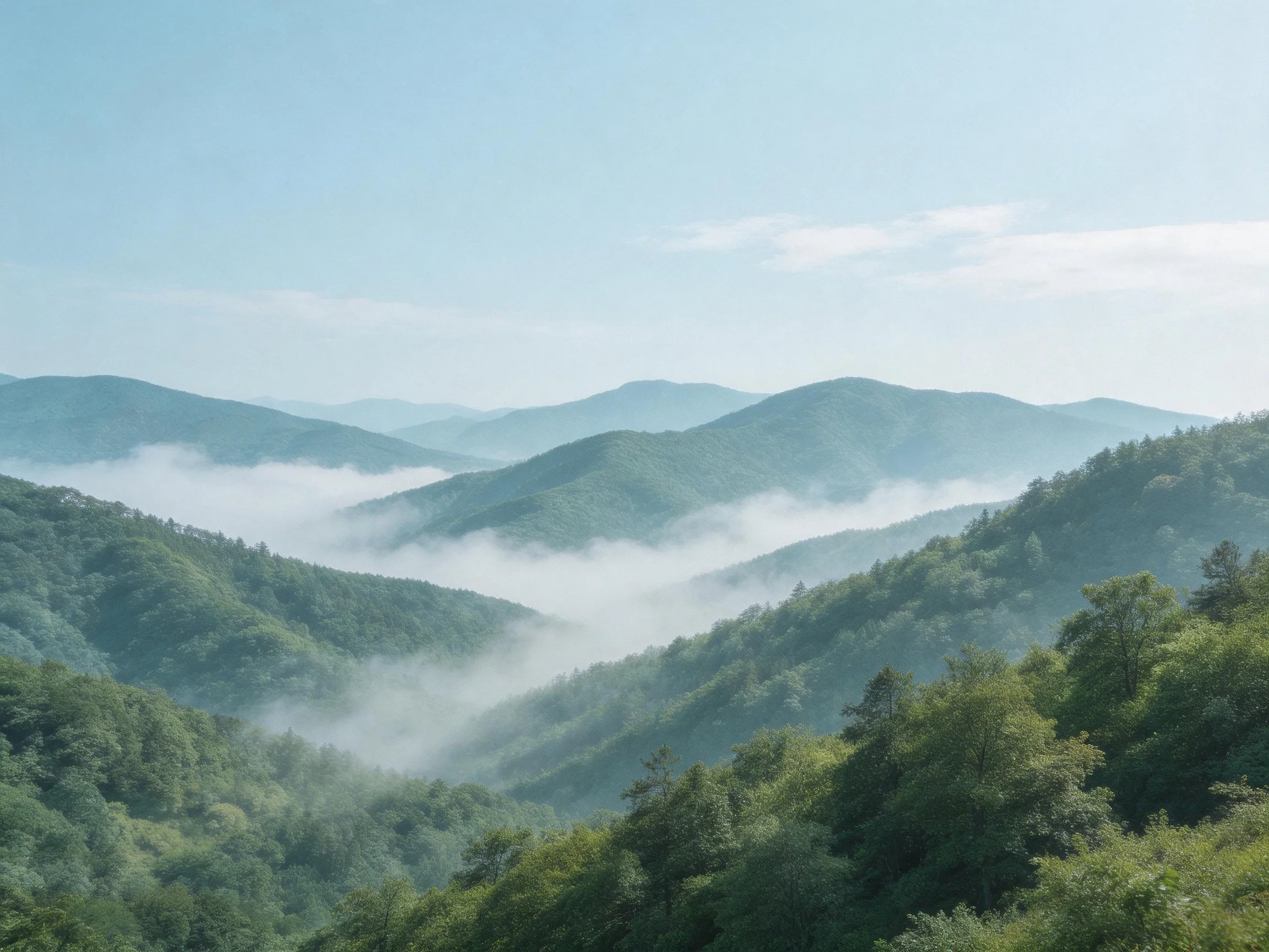 Rolling green mountains with misty valleys and clear blue skies