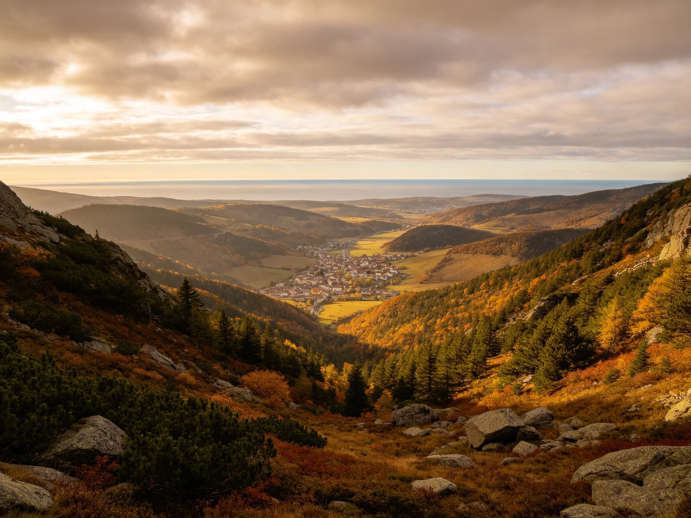 Rolling hills with autumn foliage overlook a town in a valley.
