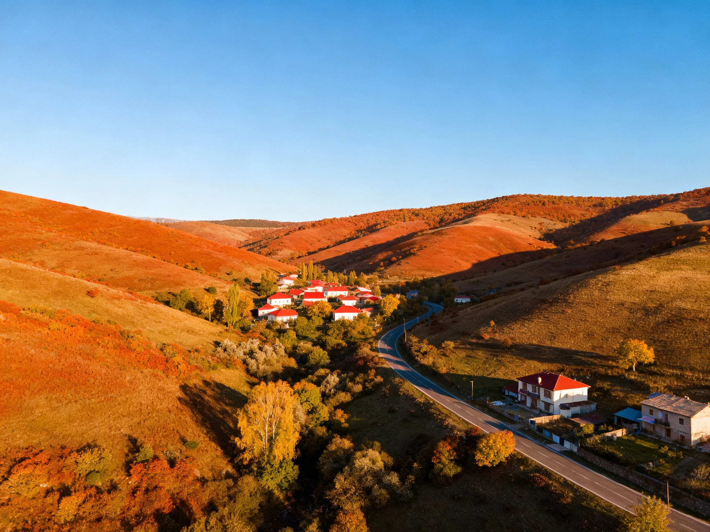 Rolling reddish-orange hills encircle a village of red-roofed homes